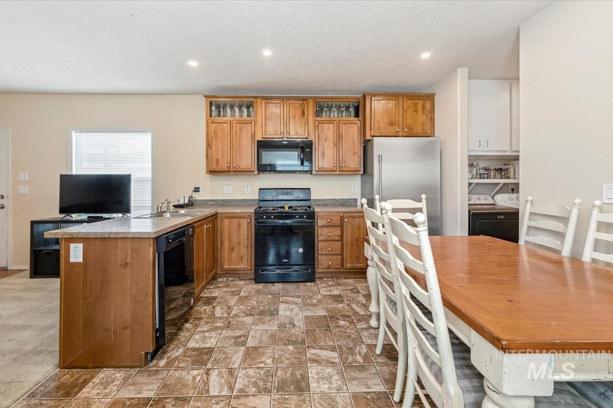 Kitchen with brown cabinets, black appliances, a peninsula, light countertops, and recessed lighting