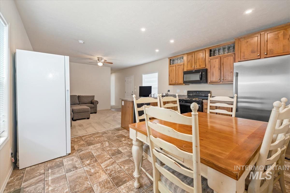 Kitchen with brown cabinetry, black appliances, light countertops, recessed lighting, and a ceiling fan