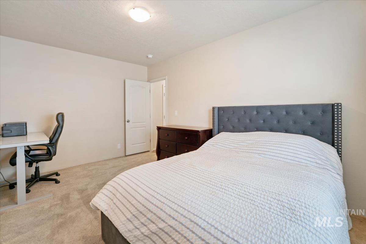 Bedroom featuring light colored carpet, an office area, and a textured ceiling