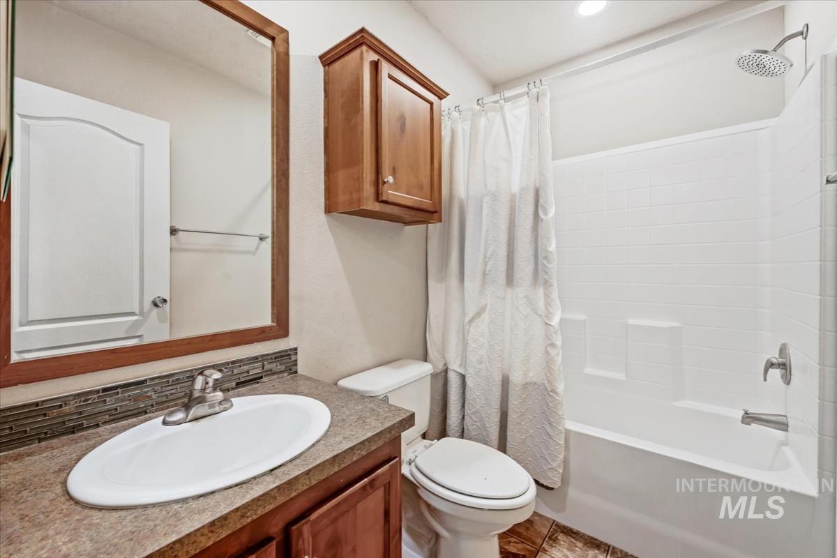 Full bath with shower / tub combo, vanity, tasteful backsplash, and tile patterned flooring