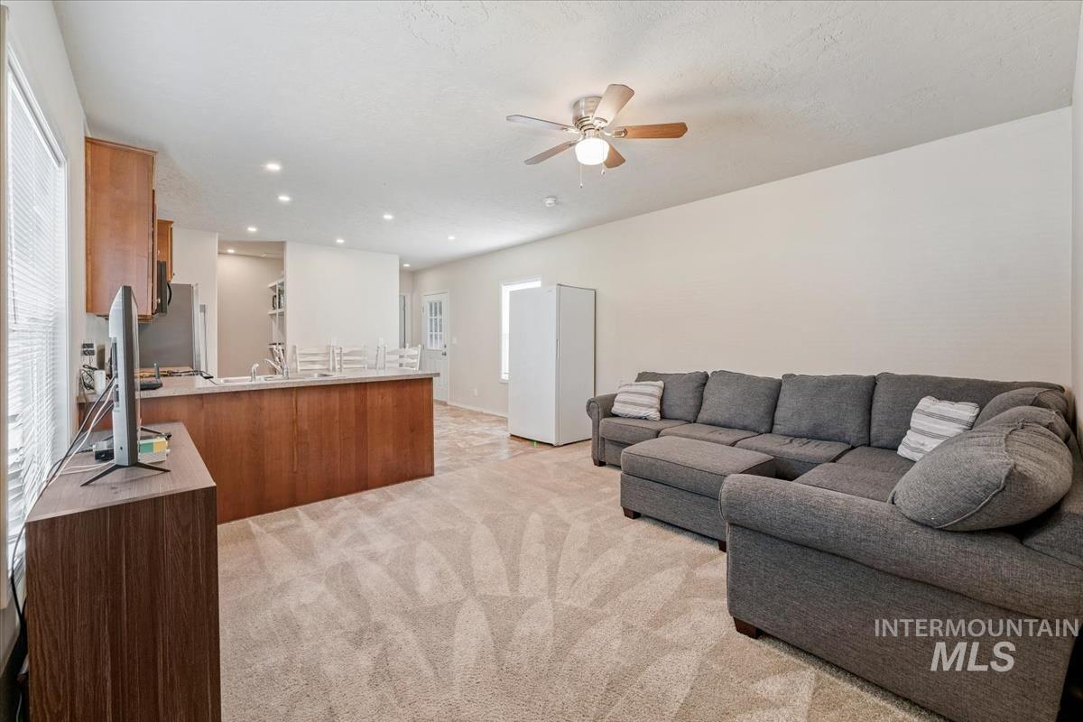Living room with light colored carpet, recessed lighting, plenty of natural light, and ceiling fan