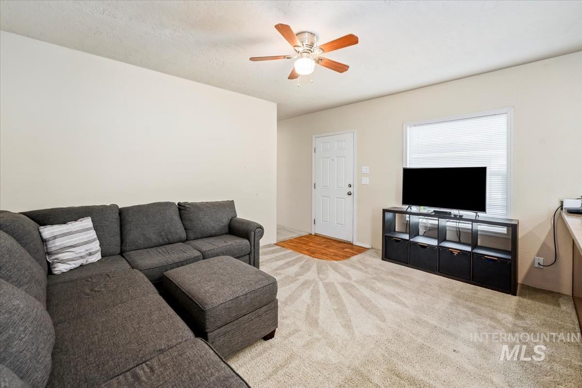 Carpeted living area with ceiling fan