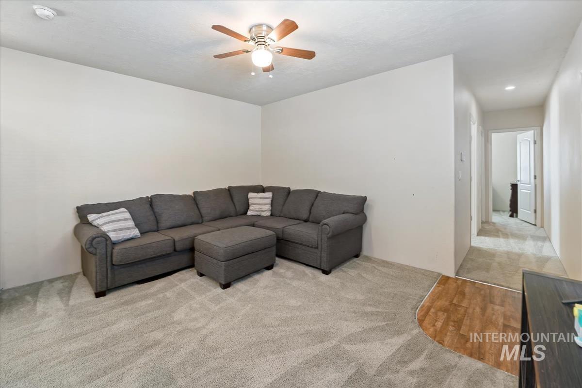 Living area with light colored carpet and ceiling fan