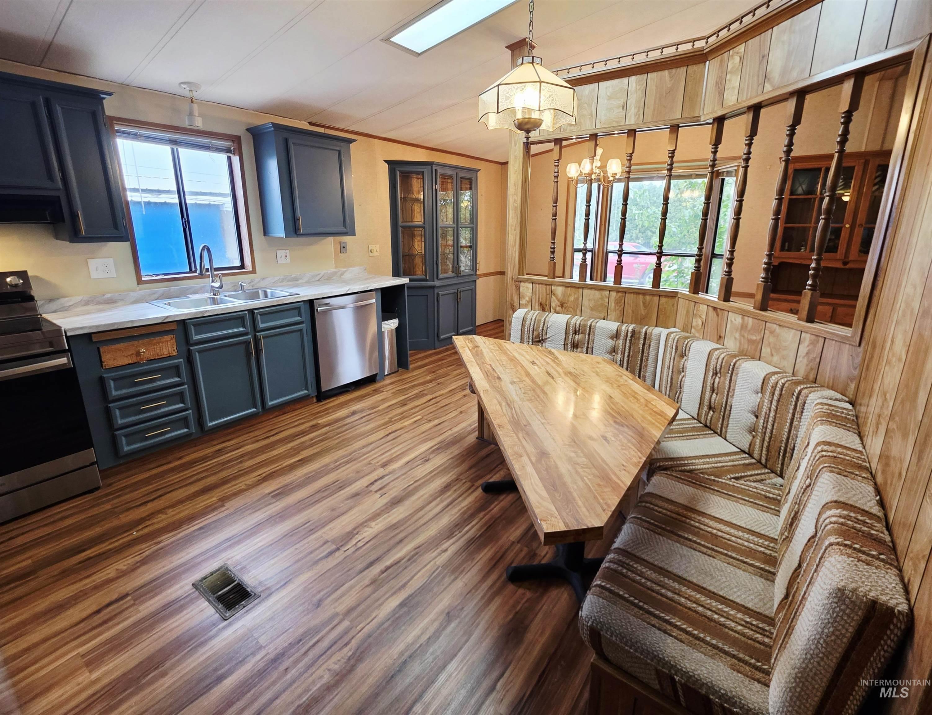 Kitchen with stainless steel appliances, dark wood-style floors, crown molding, hanging light fixtures, and a chandelier