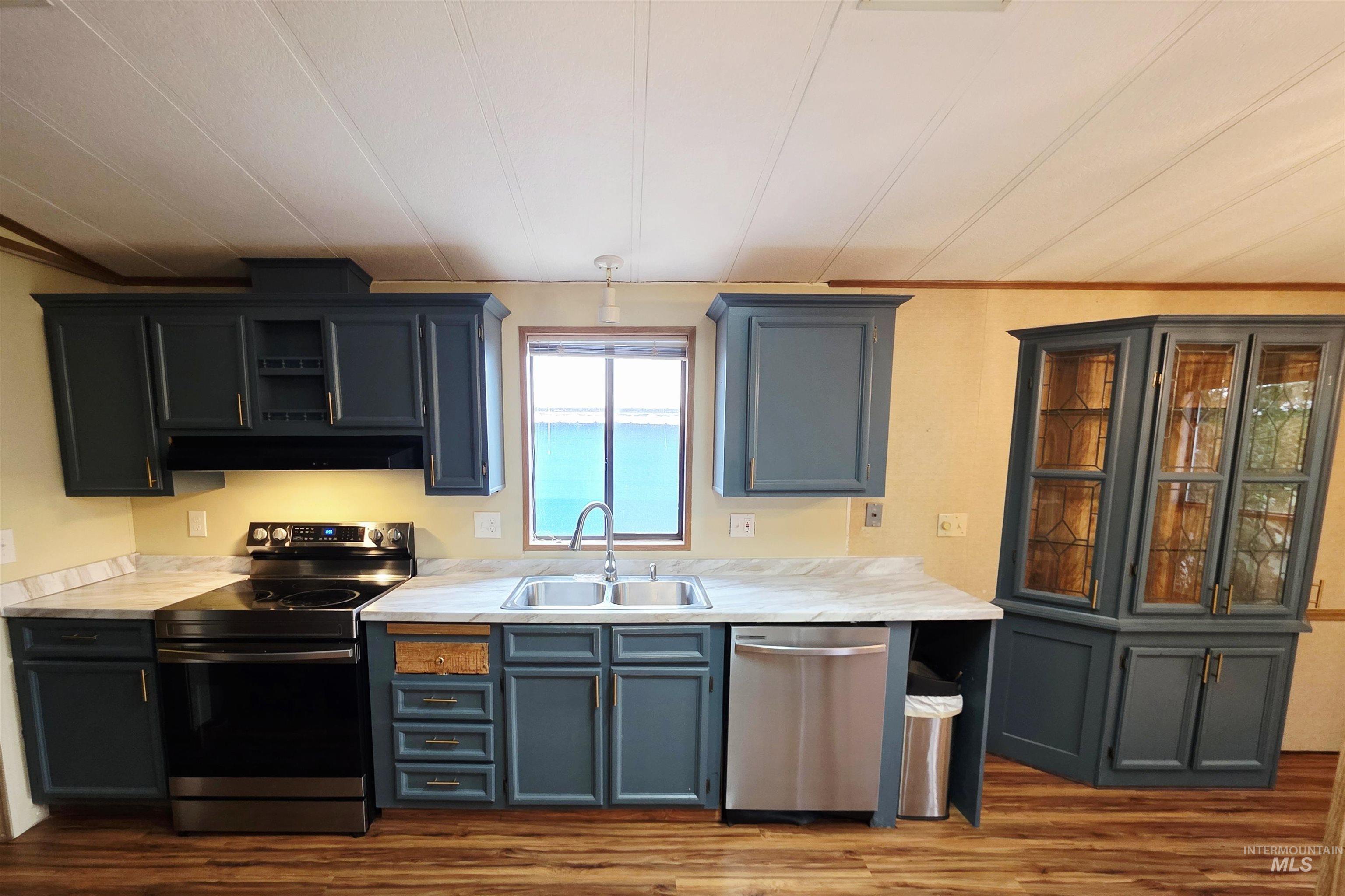 Kitchen featuring stainless steel appliances, light countertops, dark wood-style floors, and gray cabinets
