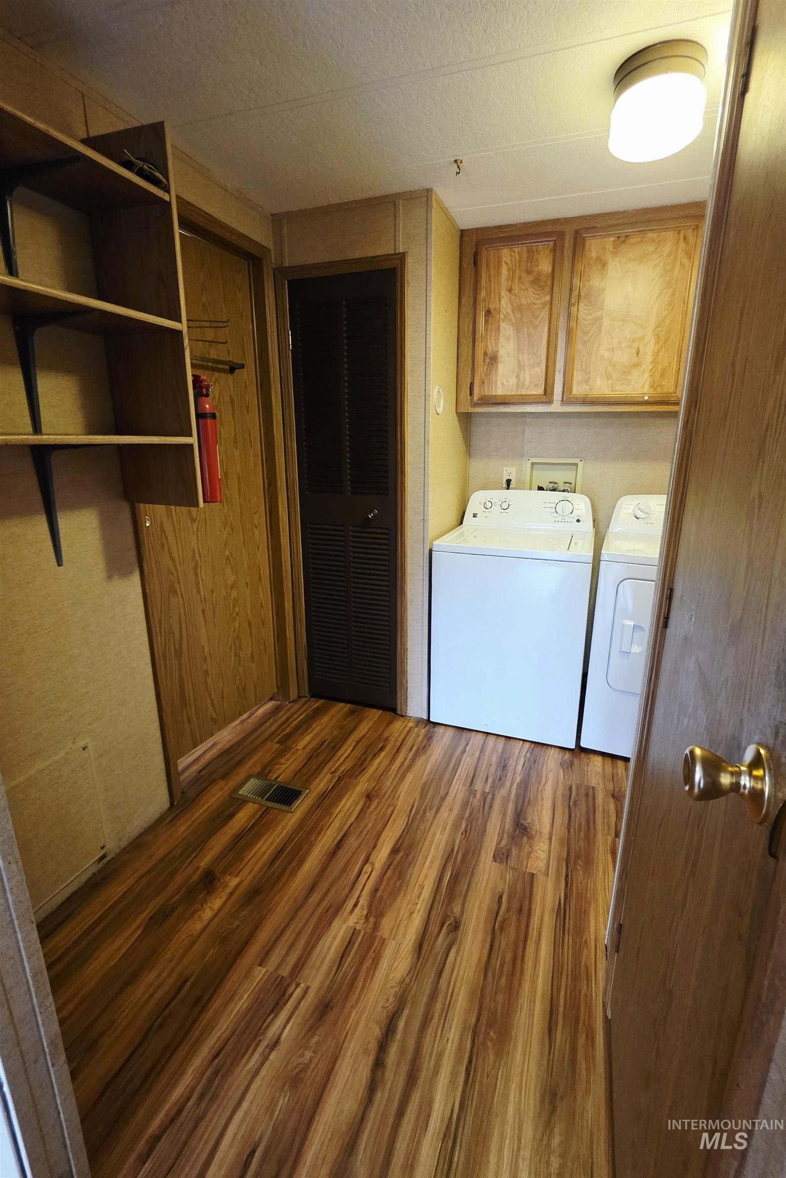 Washroom featuring dark wood-style floors, cabinet space, and separate washer and dryer