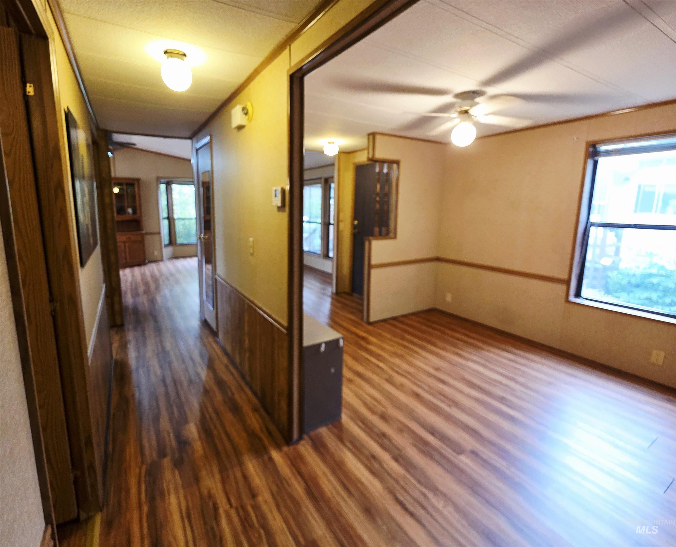 Hall featuring dark wood-style flooring and a wainscoted wall