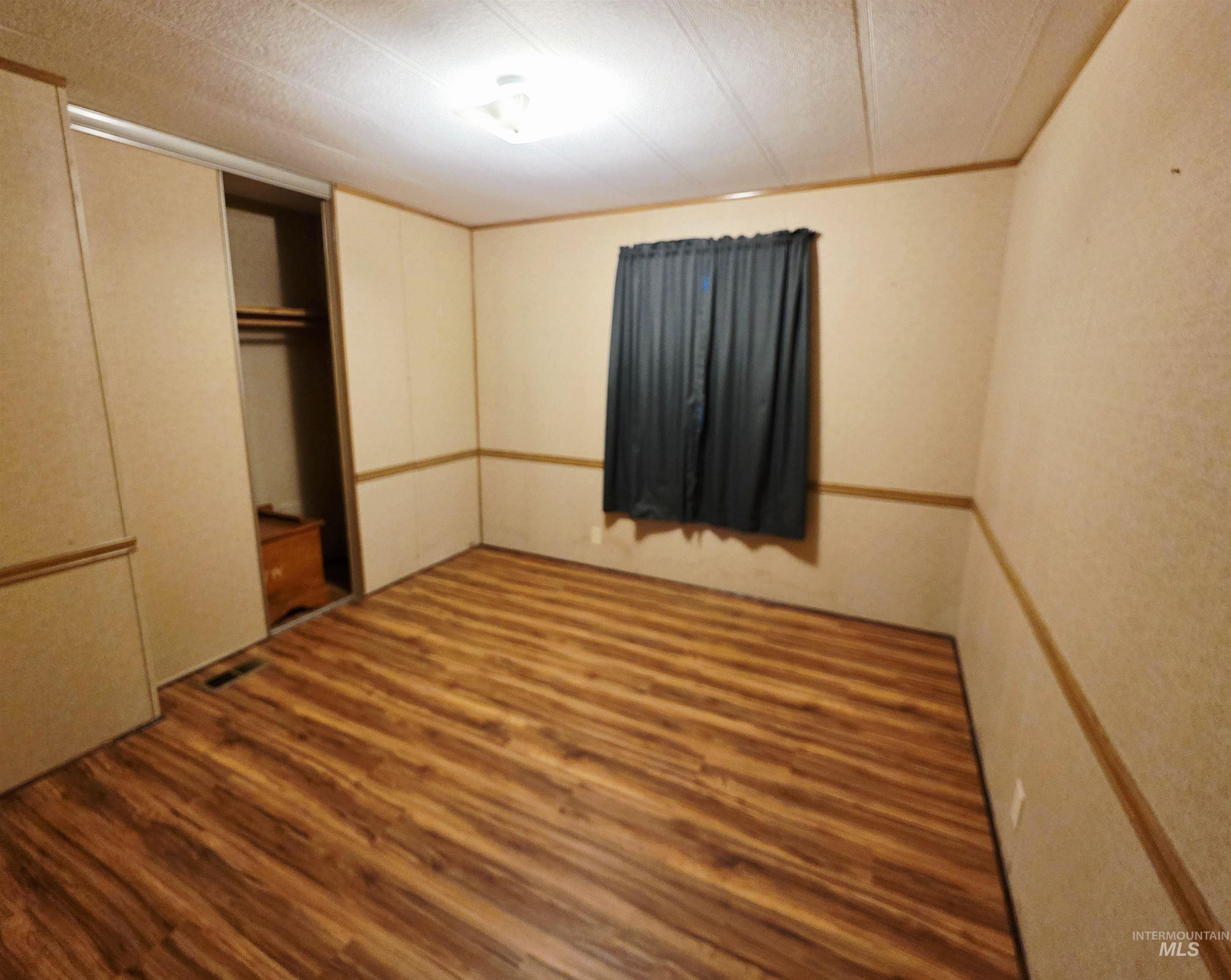 Unfurnished bedroom featuring wood finished floors, a textured ceiling, a closet, and ornamental molding