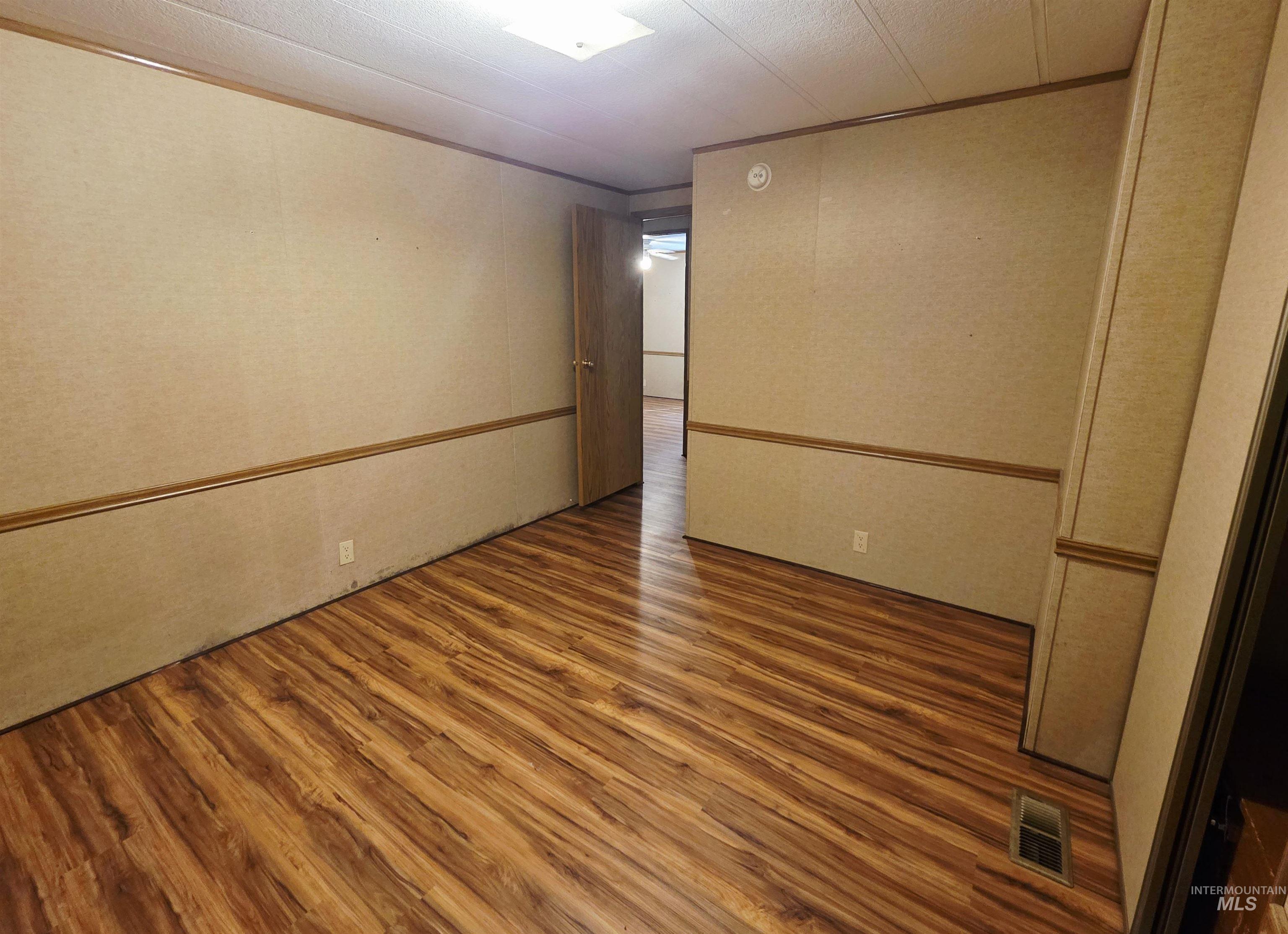 Spare room with wood finished floors and crown molding