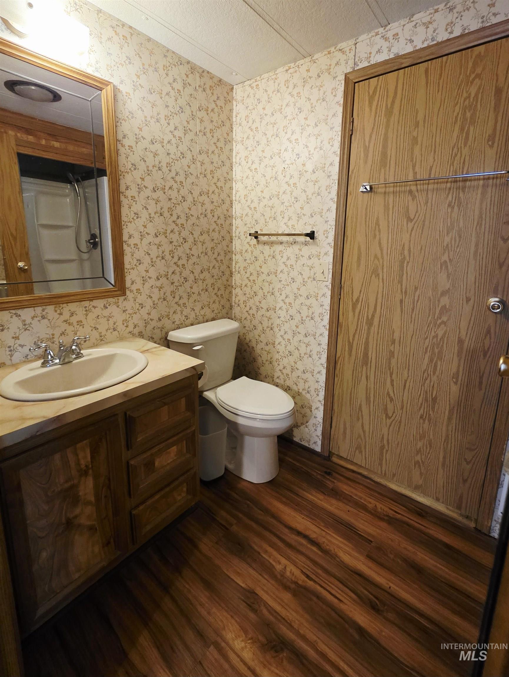 Full bath with dark wood-style flooring, vanity, and a textured ceiling