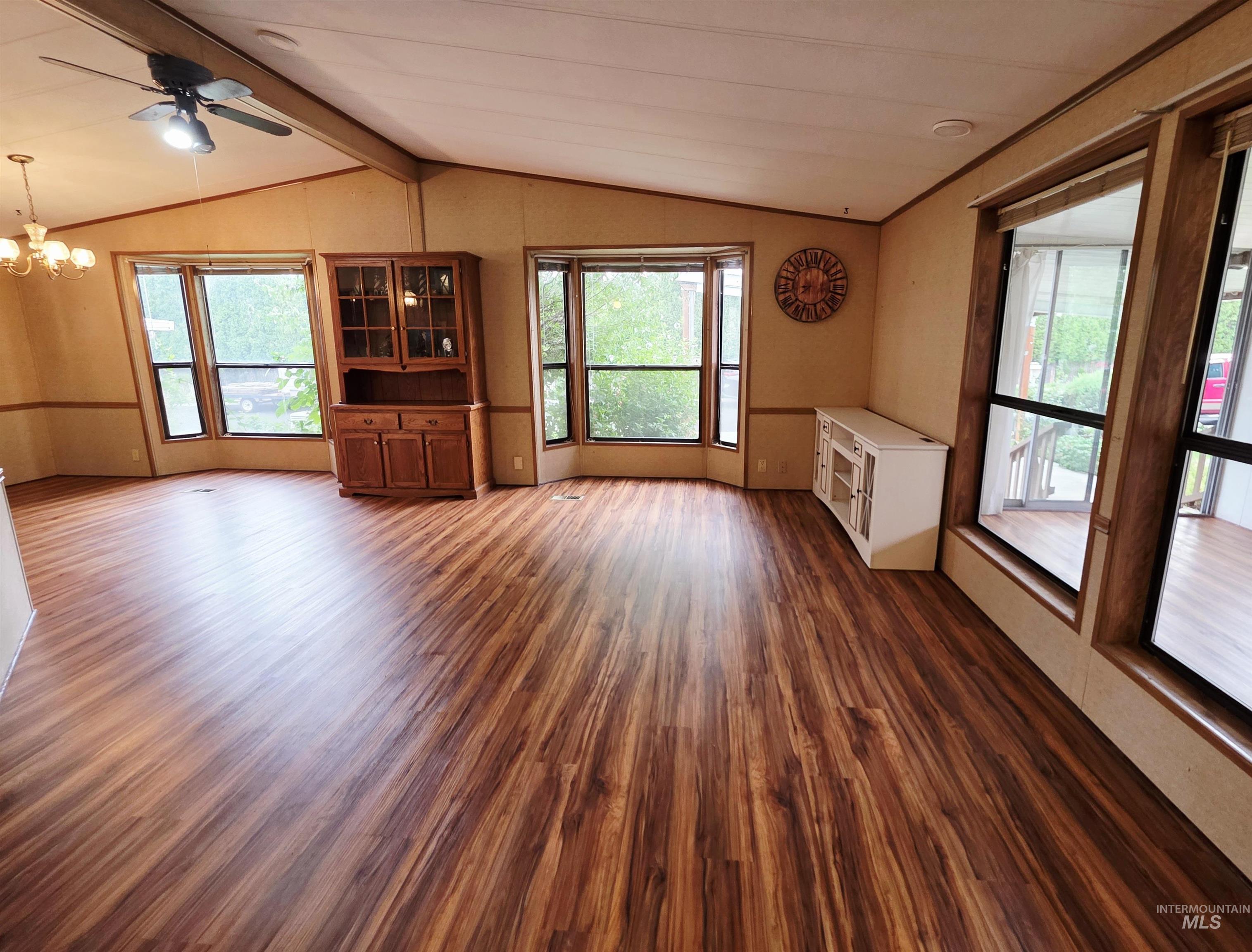 Unfurnished living room with dark wood finished floors, a chandelier, and ceiling fan