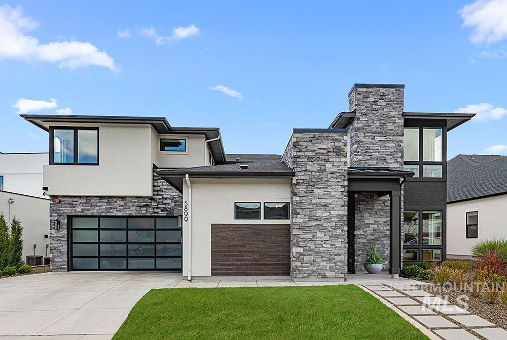 Contemporary home featuring stone siding, concrete driveway, a front yard, stucco siding, and a garage
