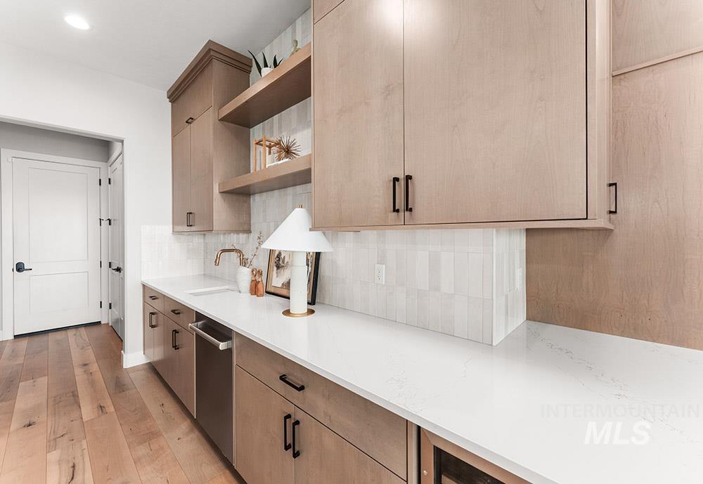 Kitchen with open shelves, light wood-style floors, decorative backsplash, light stone counters, and stainless steel dishwasher