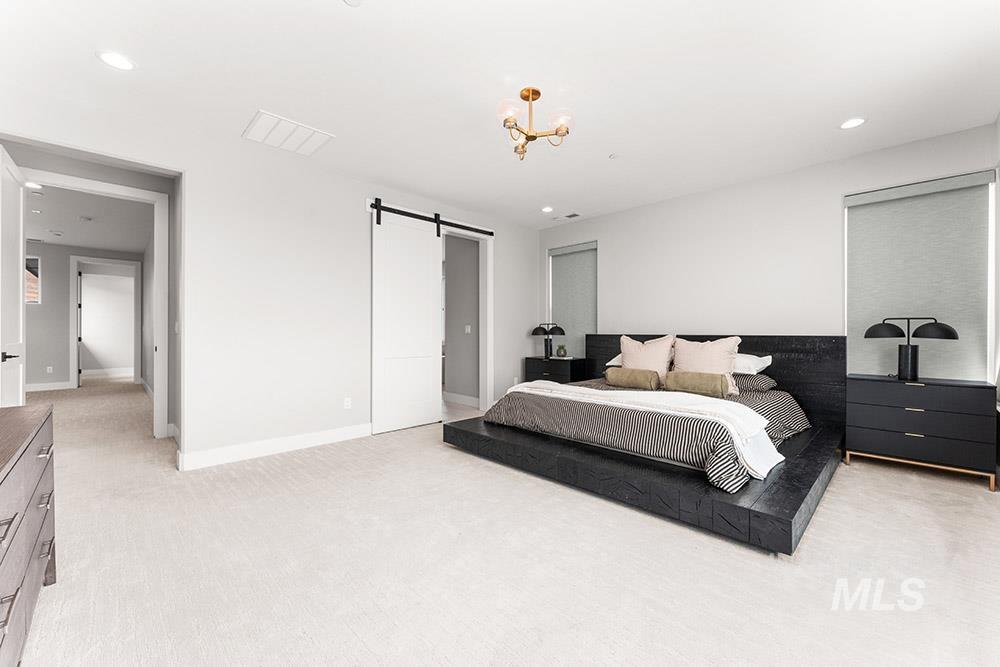 Bedroom featuring a barn door, light colored carpet, and recessed lighting