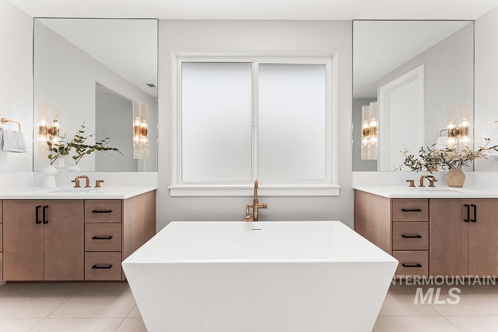 Full bathroom featuring two vanities, light tile patterned floors, and a soaking tub