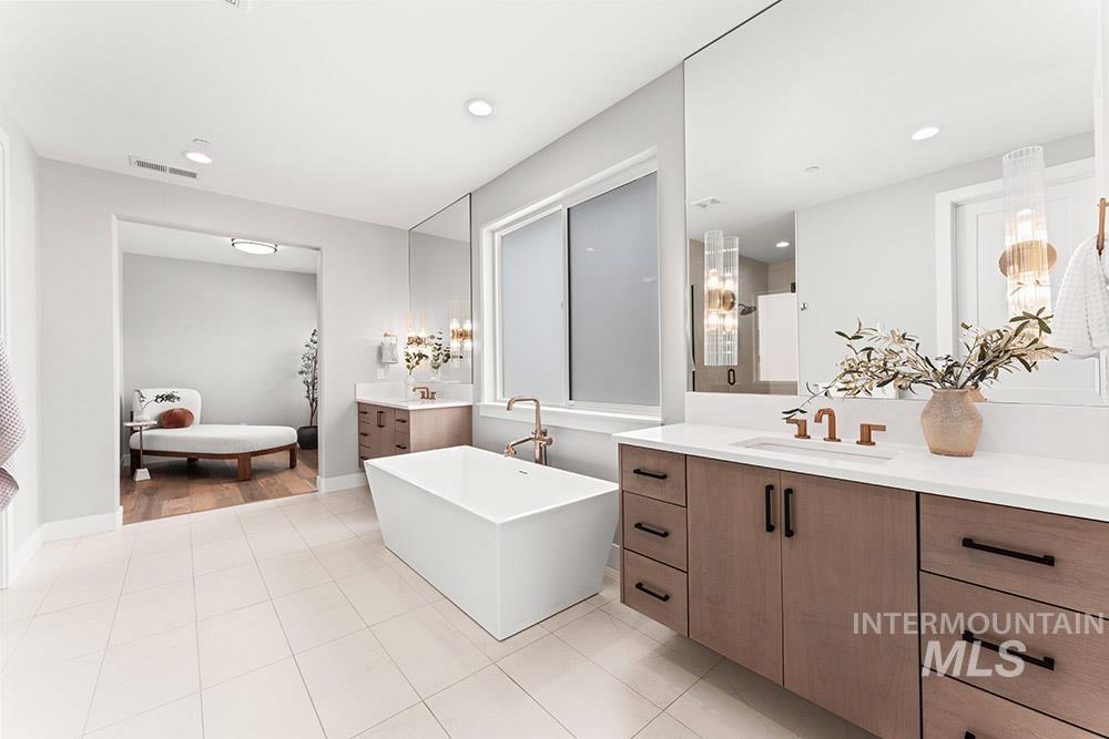 Bathroom with two vanities, a freestanding bath, light tile patterned floors, and recessed lighting
