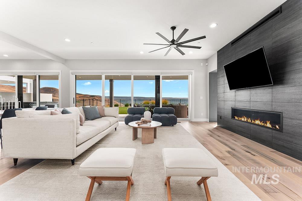 Living area with light wood finished floors, a tile fireplace, recessed lighting, and a ceiling fan