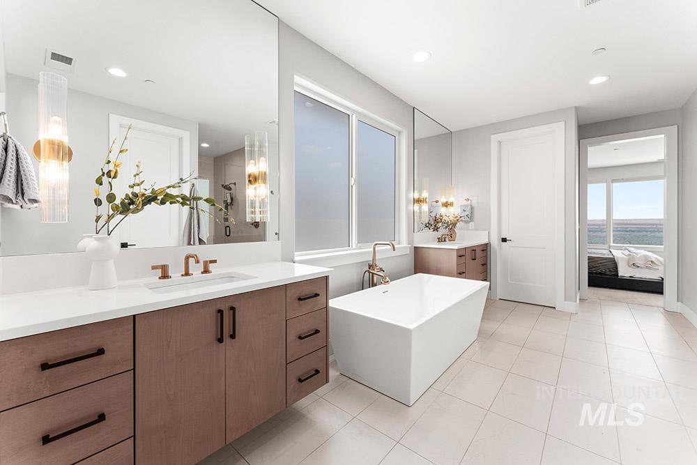 Bathroom featuring vanity, a freestanding tub, light tile patterned floors, ensuite bath, and recessed lighting