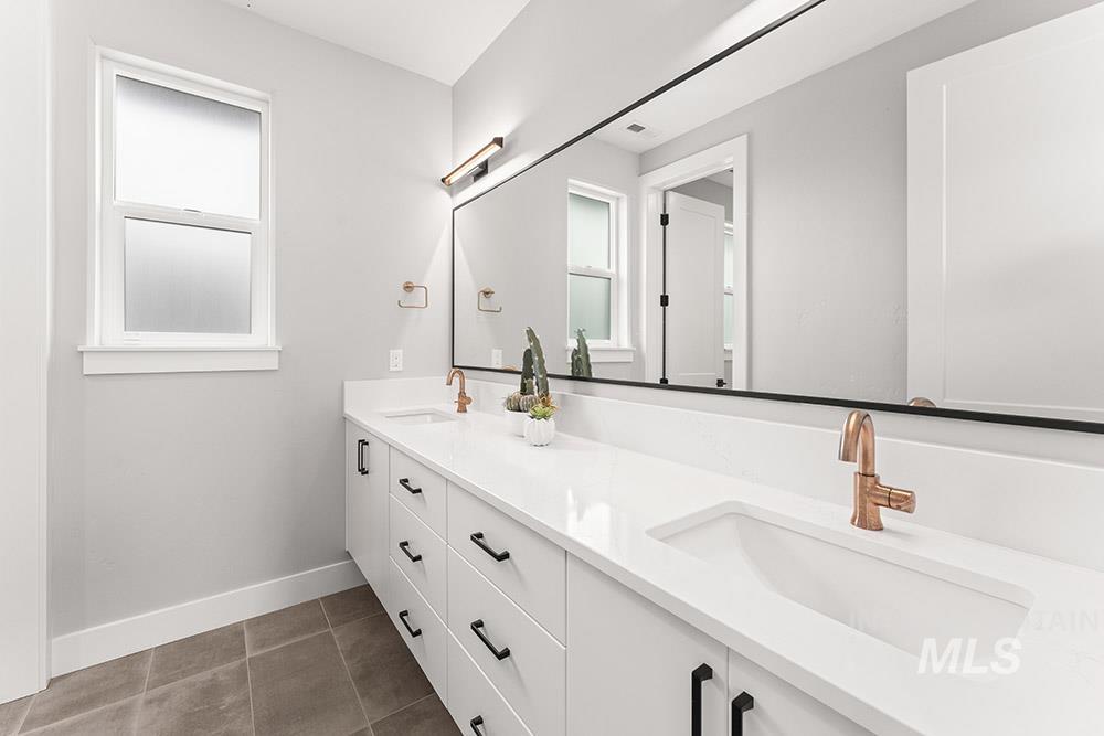 Full bath with double vanity and dark tile patterned floors