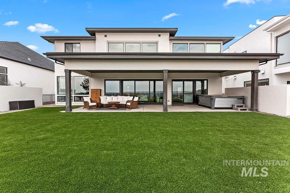 Rear view of property featuring a hot tub, stucco siding, a patio, and outdoor lounge area