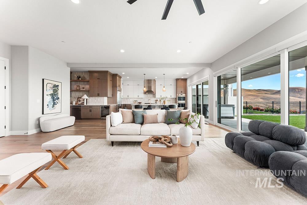 Living room with recessed lighting, light wood-style floors, beverage cooler, and a ceiling fan