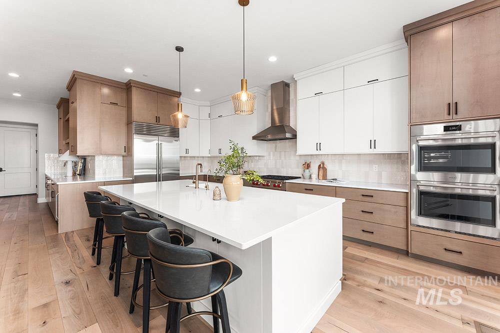 Kitchen with decorative backsplash, a center island with sink, white cabinetry, stainless steel appliances, and a kitchen breakfast bar