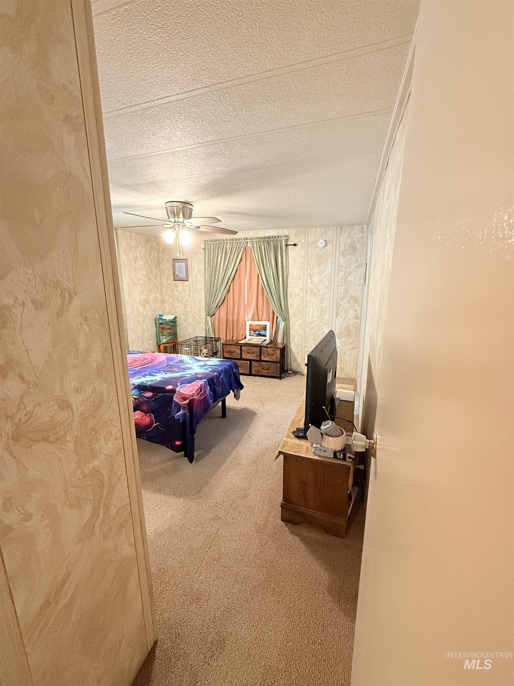 Bedroom with carpet, a textured ceiling, and wallpapered walls