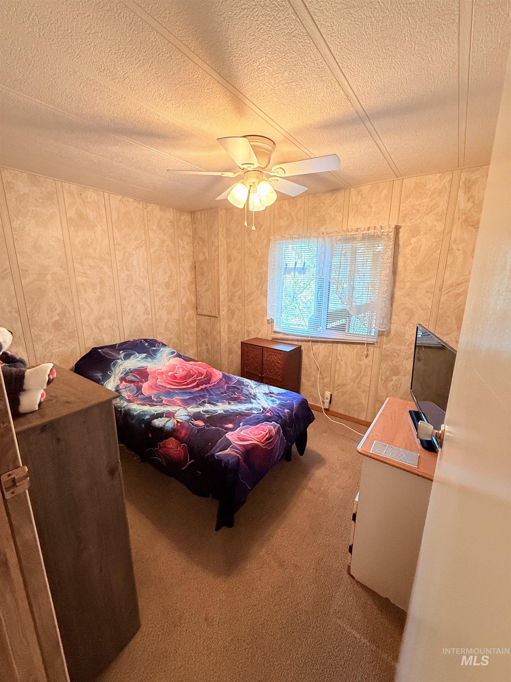 Bedroom featuring carpet floors, ceiling fan, and a textured ceiling