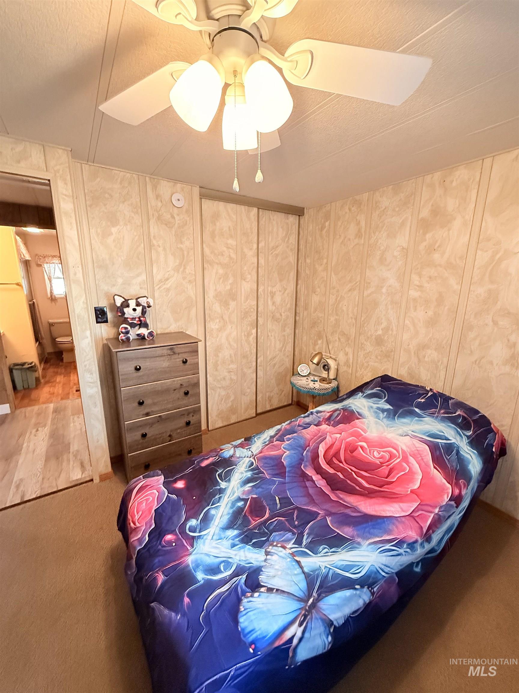 Carpeted bedroom with a ceiling fan