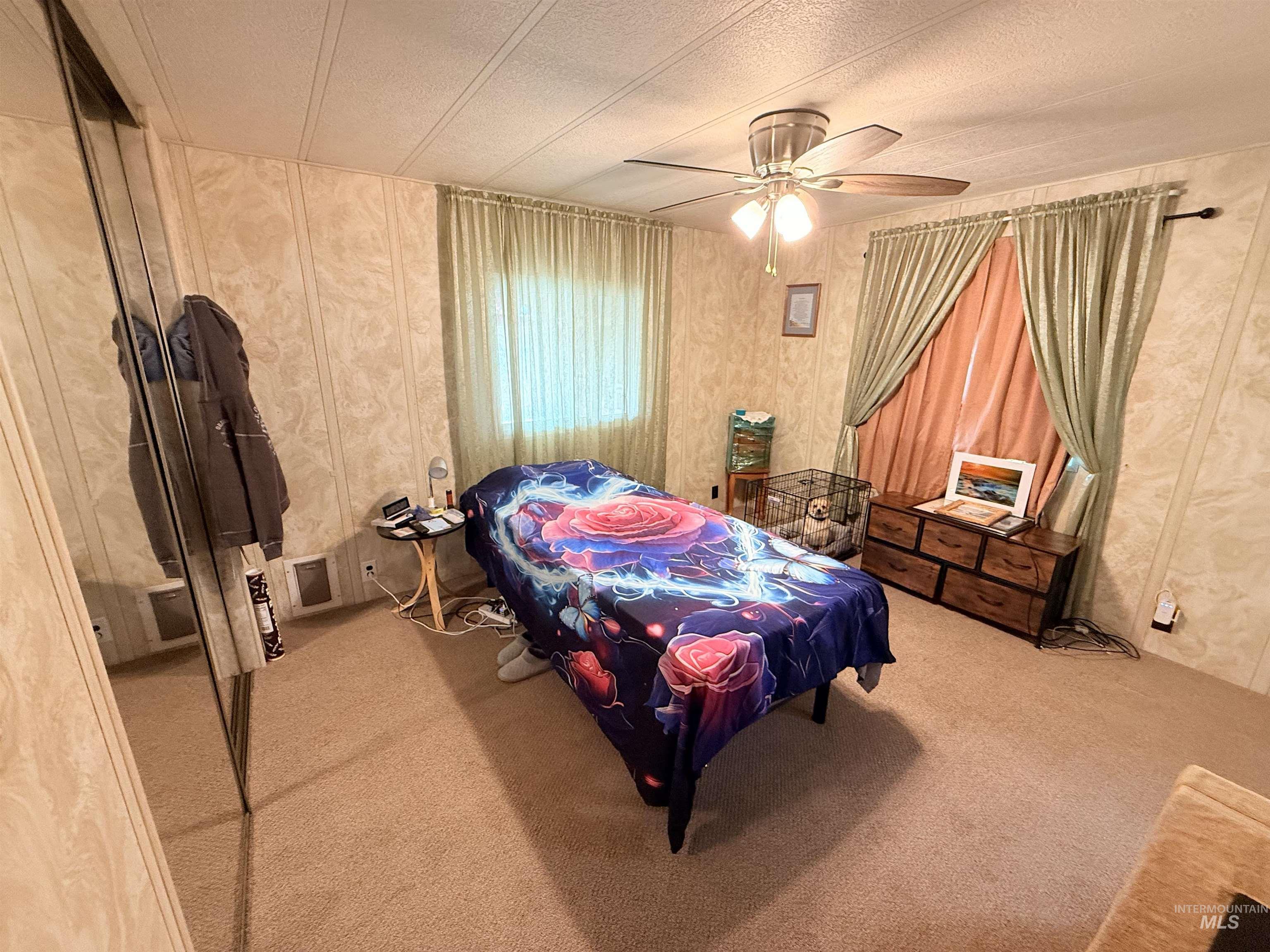 Carpeted bedroom with ceiling fan and a textured ceiling