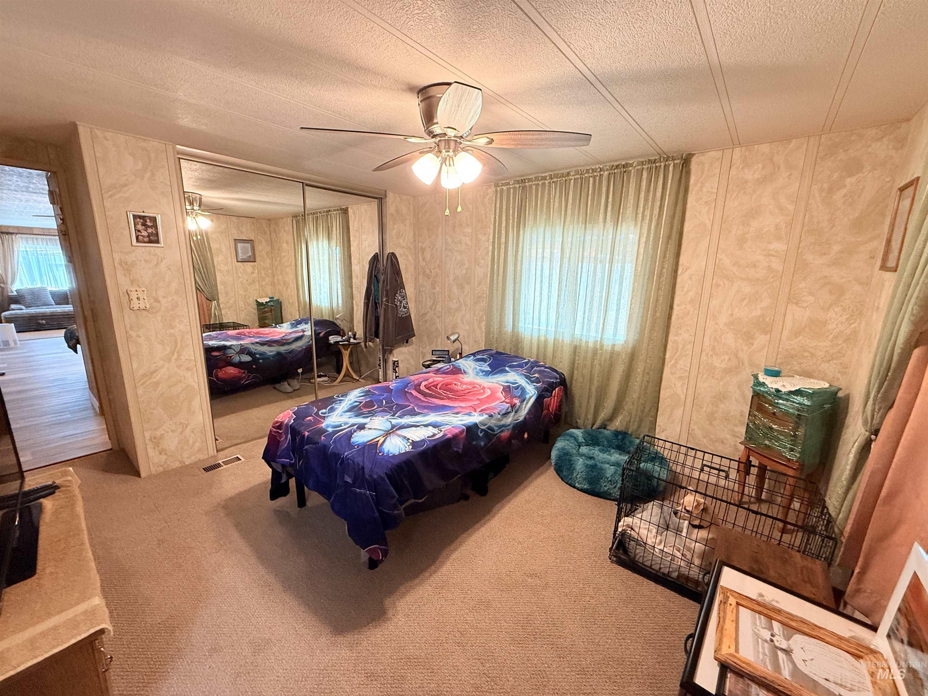 Carpeted bedroom with a ceiling fan, a textured ceiling, a closet, and heating unit