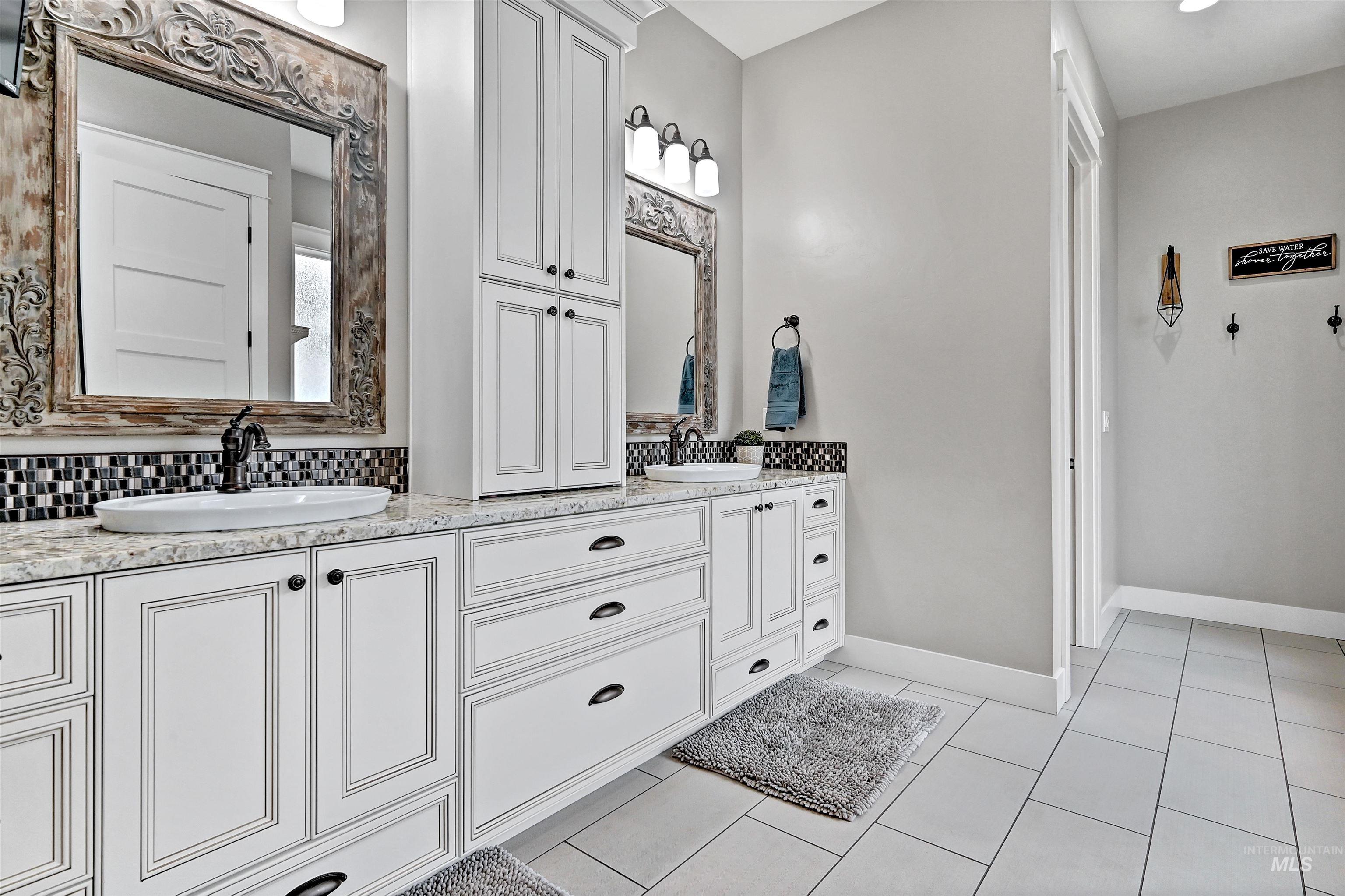 Full bathroom featuring double vanity, light tile patterned floors, and tasteful backsplash