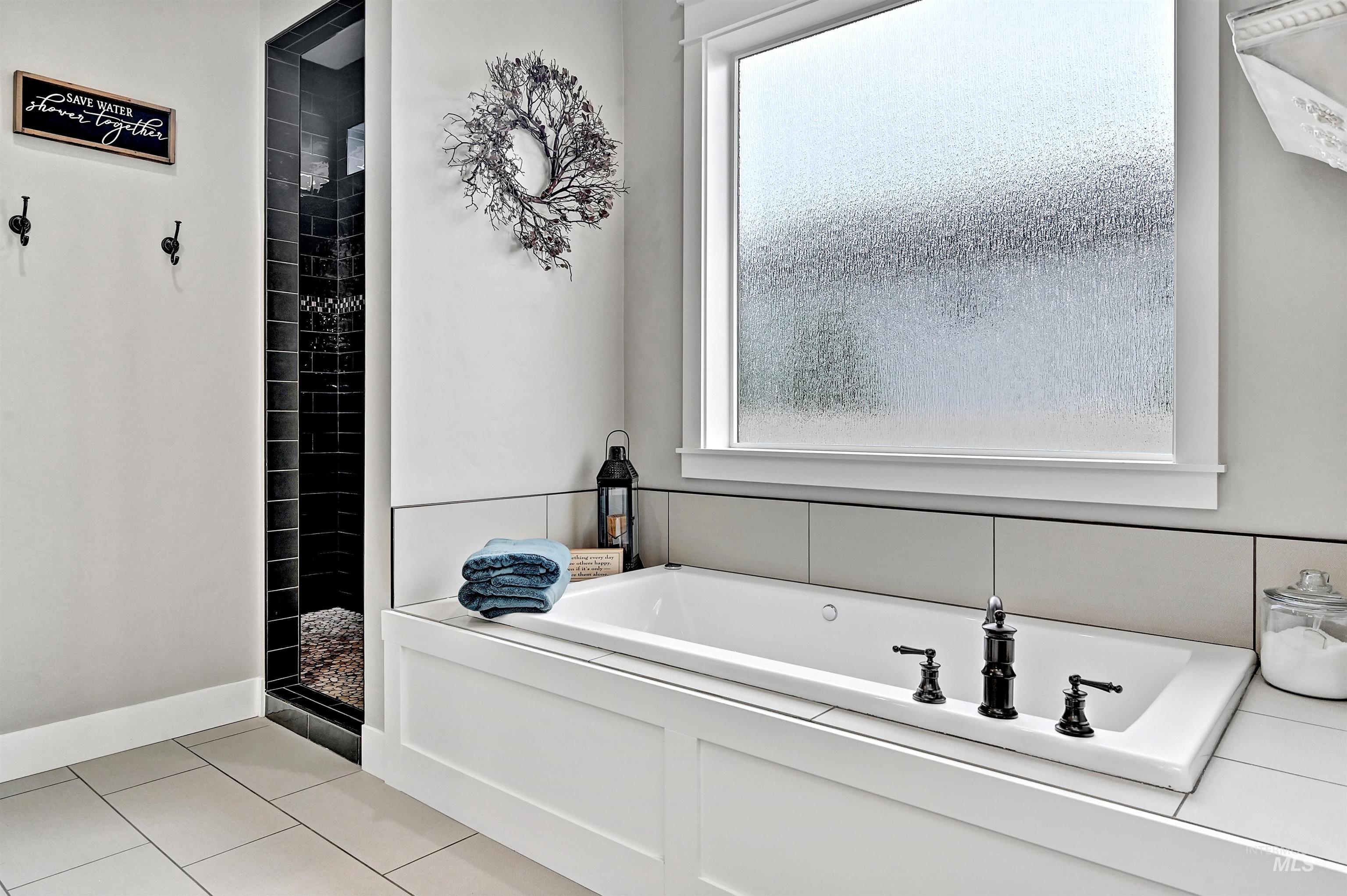 Bathroom with a bath, tile patterned floors, plenty of natural light, and a stall shower