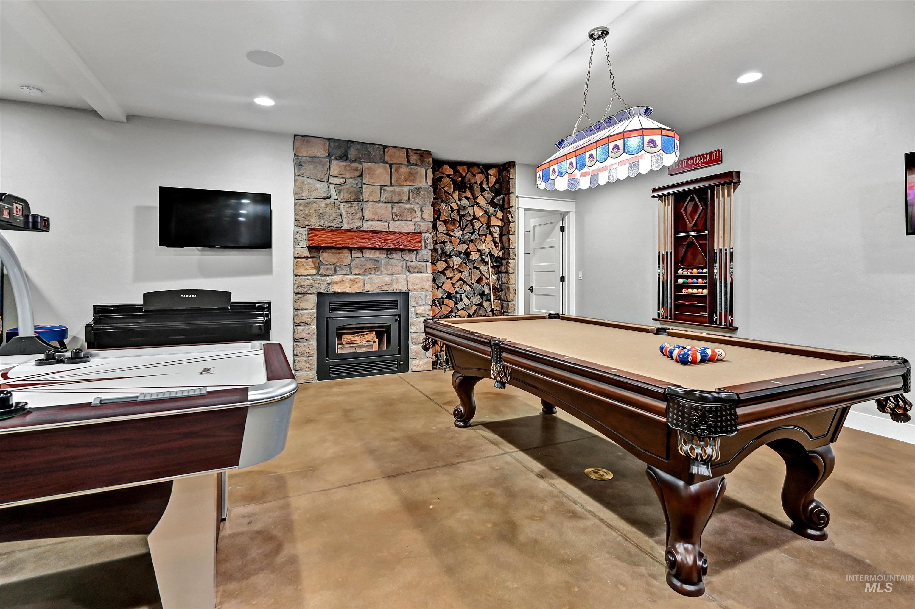 Playroom with concrete floors, a stone fireplace, pool table, and recessed lighting