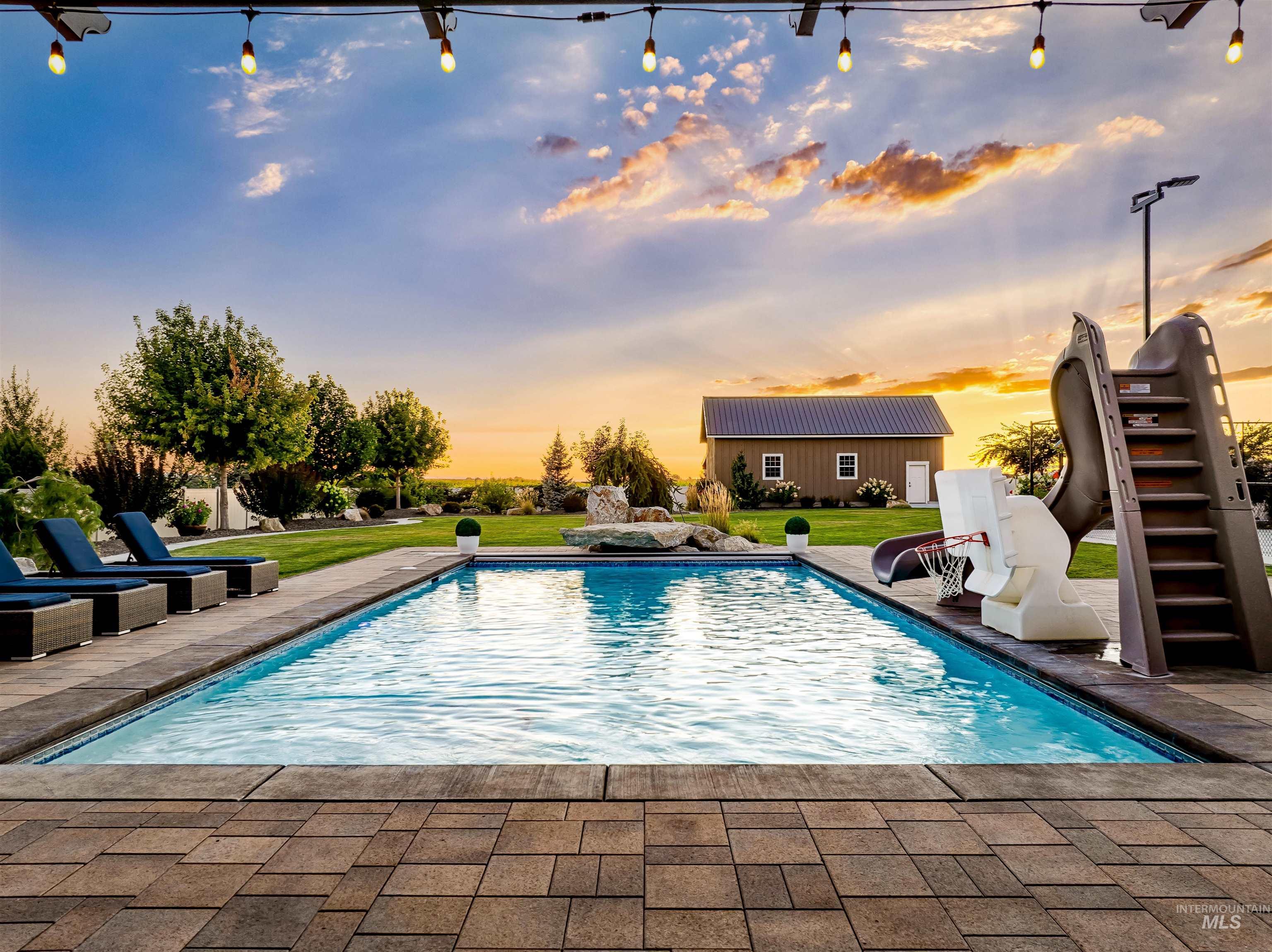 Outdoor pool with a lawn, an outdoor structure, stairs, and a patio
