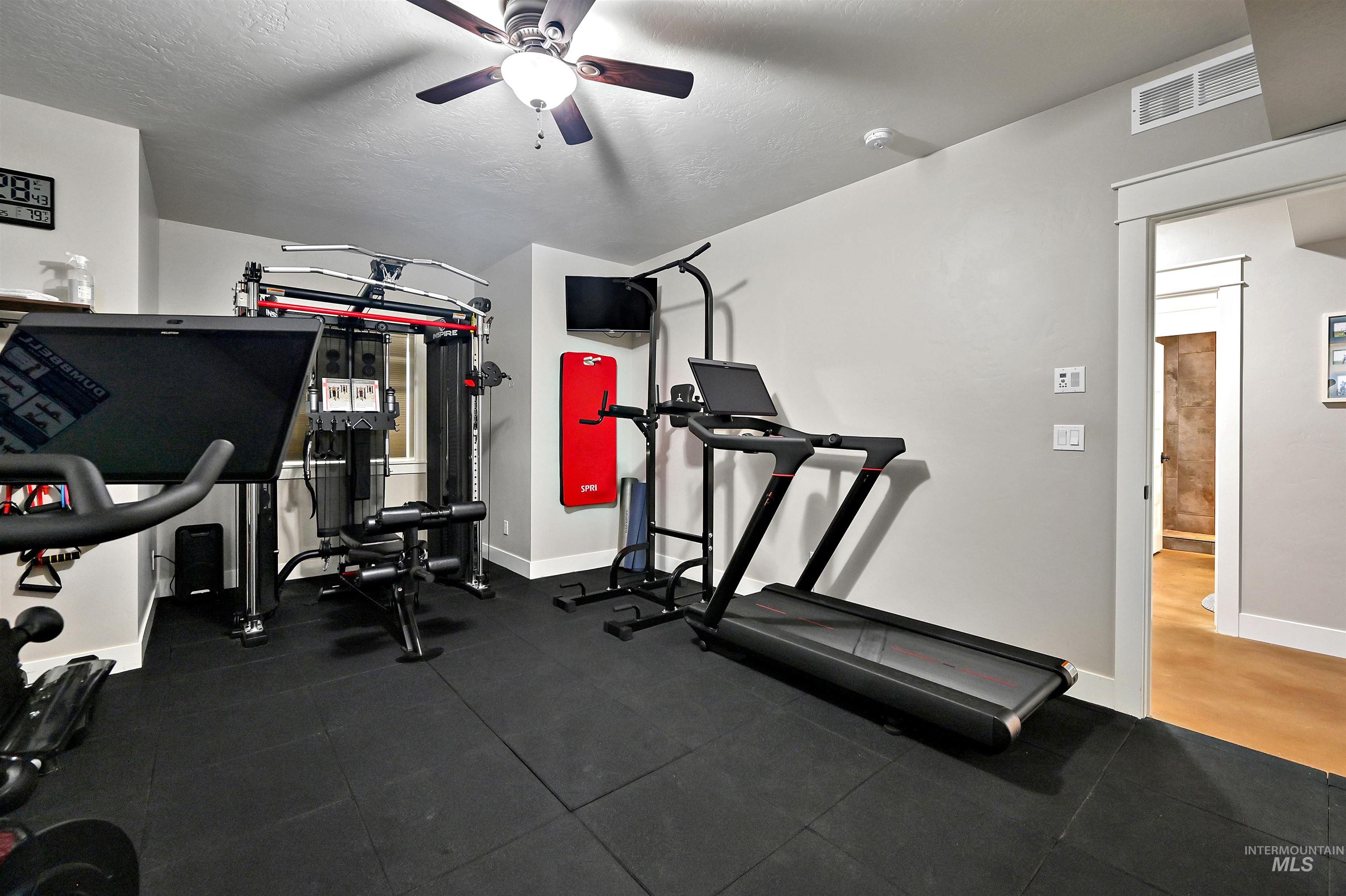 Exercise area with ceiling fan and a textured ceiling