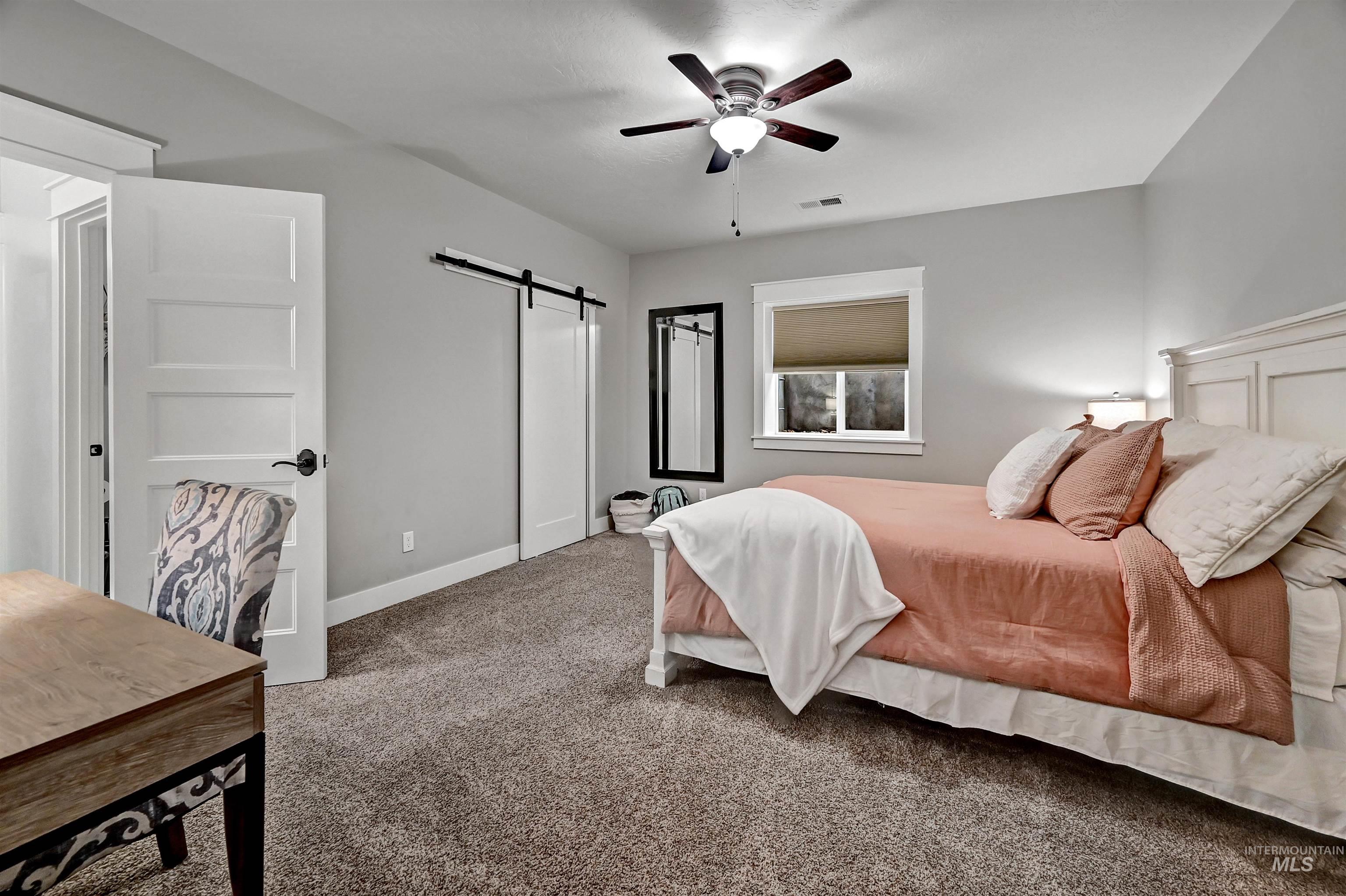 Bedroom featuring a barn door, carpet, and ceiling fan