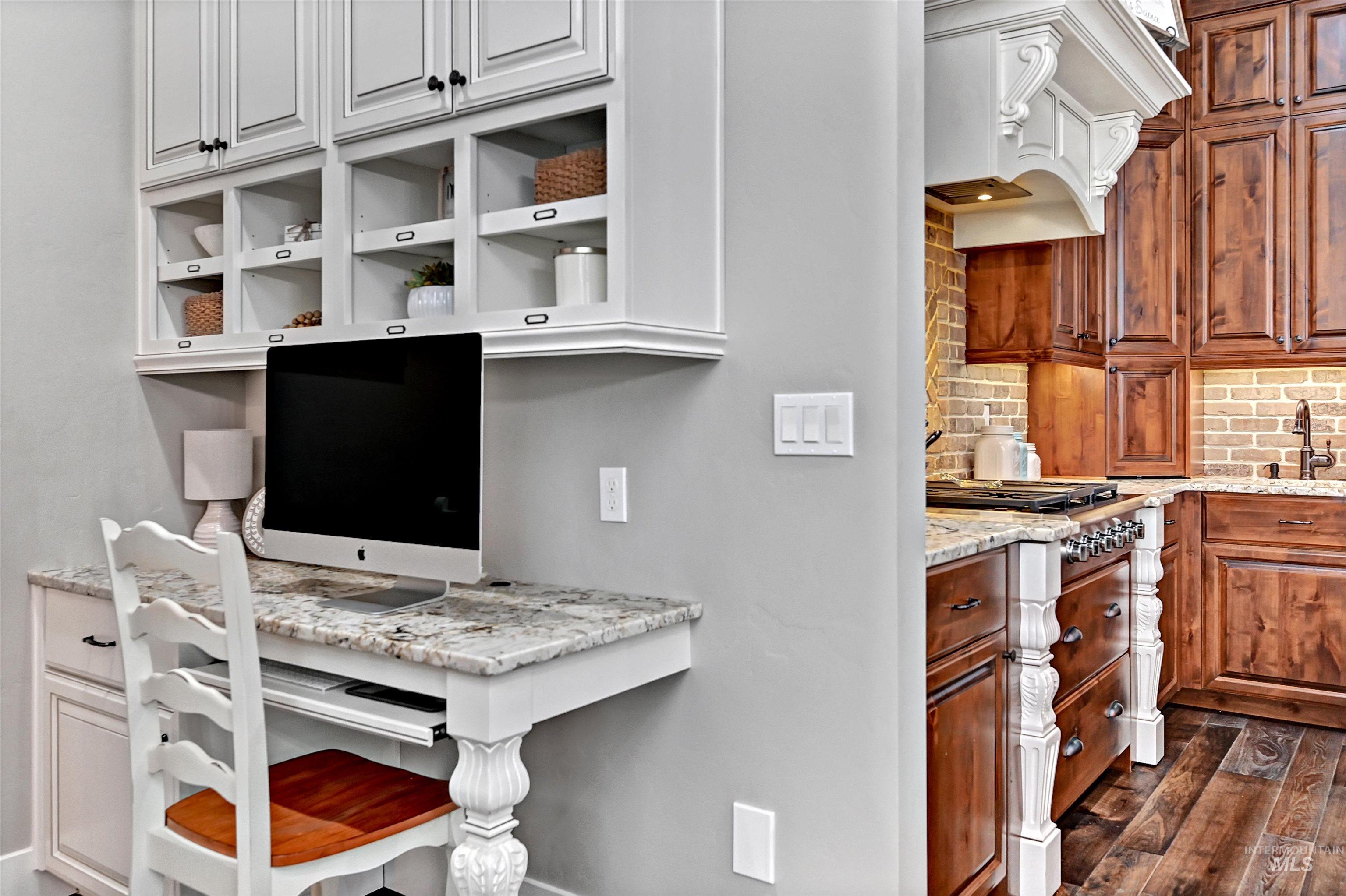 Kitchen featuring light stone countertops, backsplash, a desk, custom exhaust hood, and dark wood-style floors