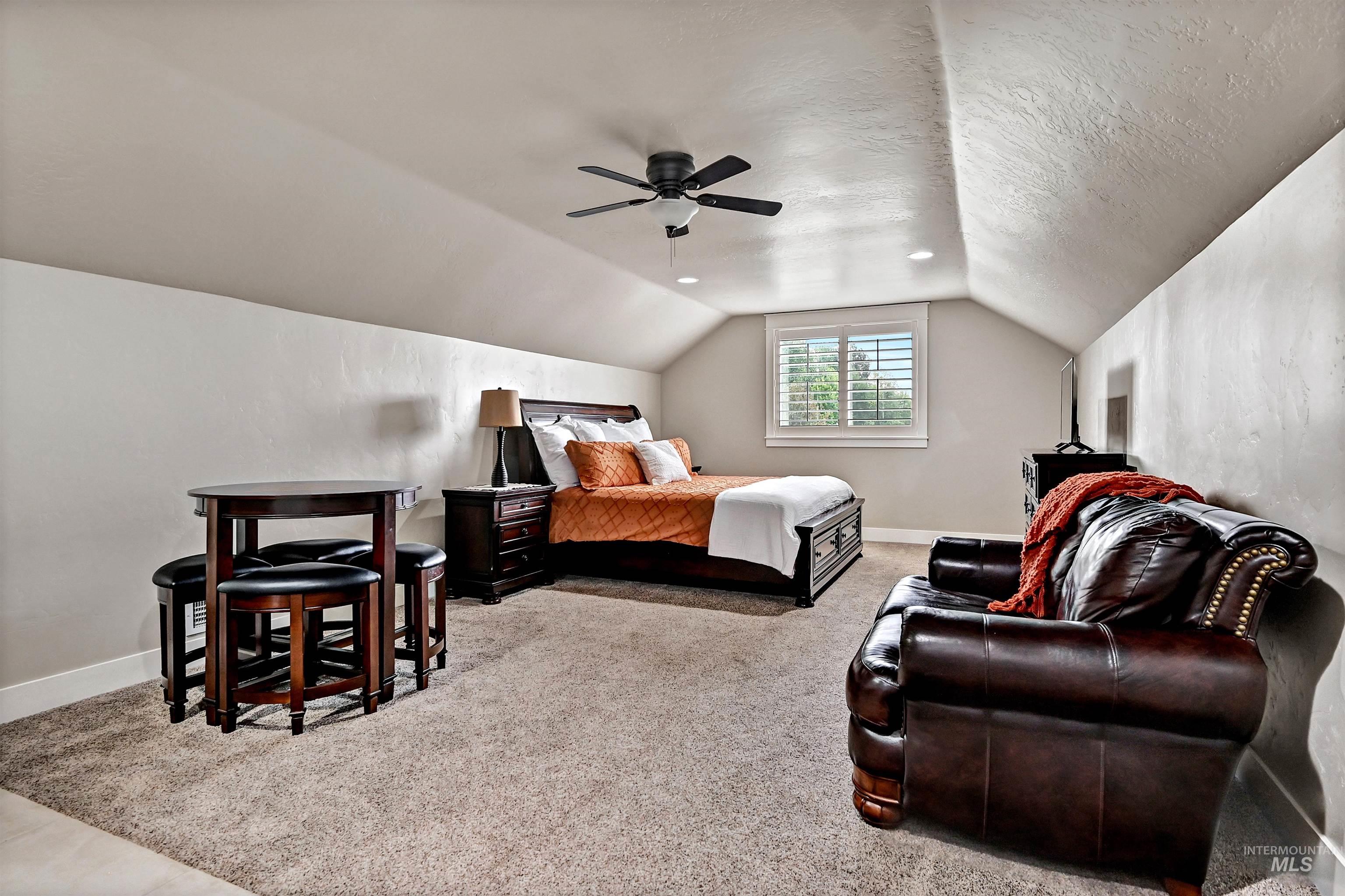 Bedroom featuring light carpet, a textured ceiling, lofted ceiling, and ceiling fan