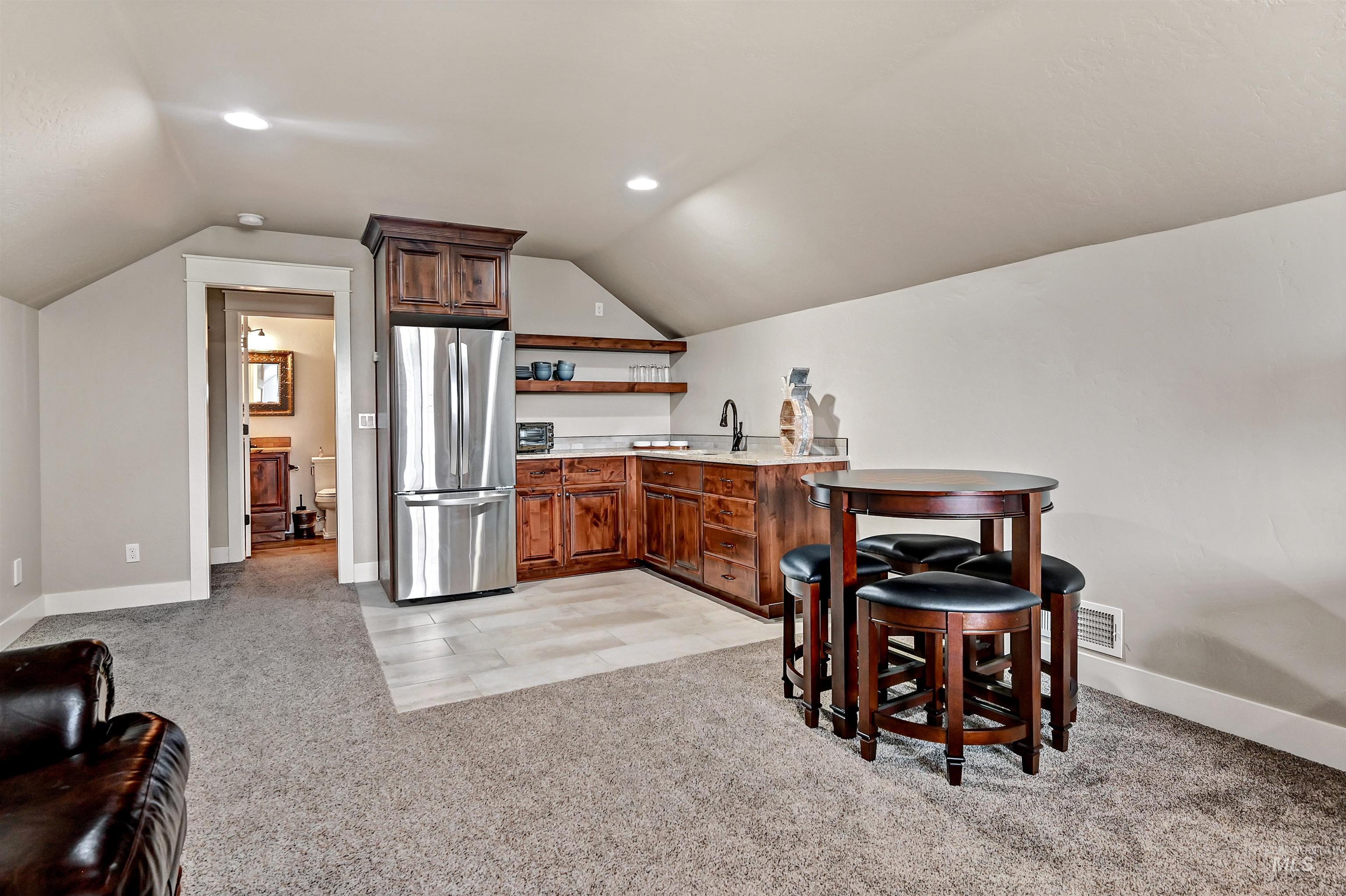 Kitchen with freestanding refrigerator, light carpet, vaulted ceiling, a peninsula, and recessed lighting