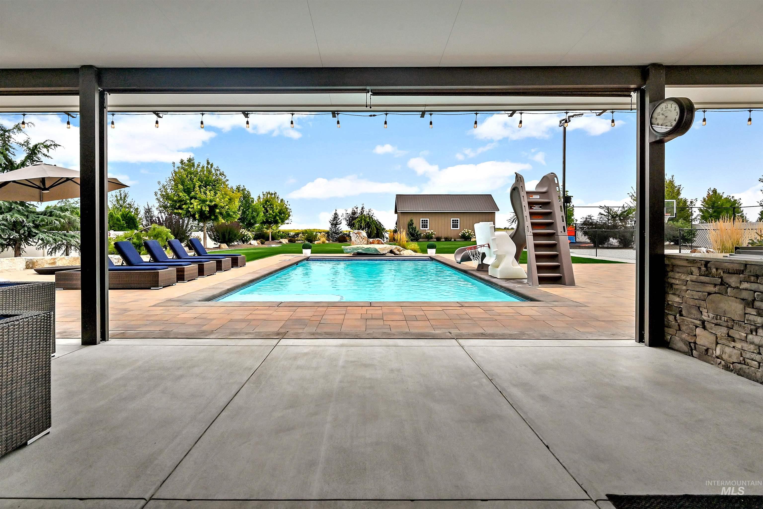 Outdoor pool featuring a water slide and a patio area