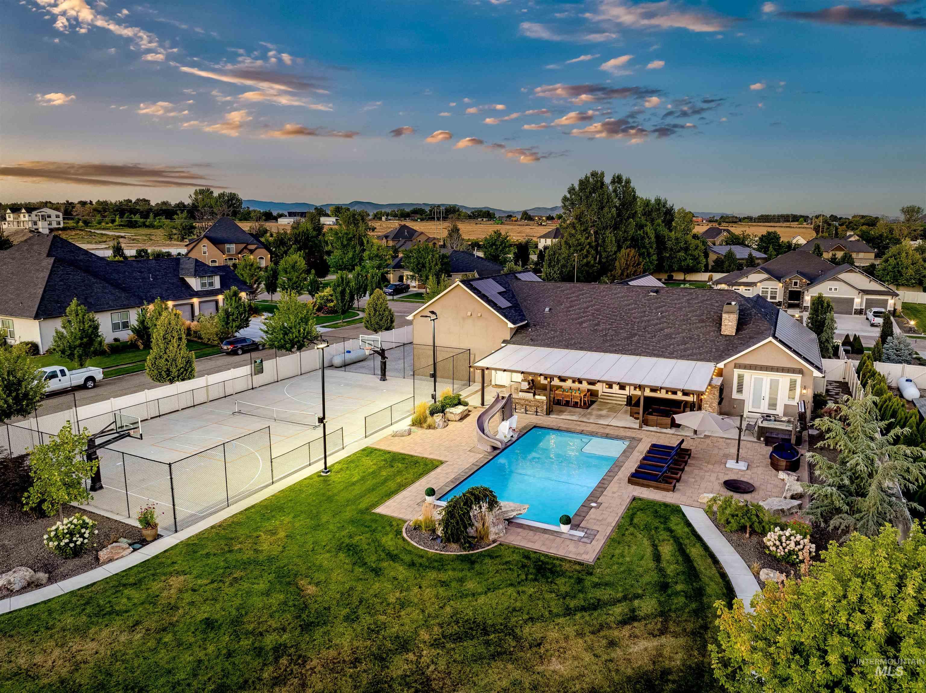Pool at dusk with a fenced backyard, a water slide, an outdoor living space, a patio, and a residential view