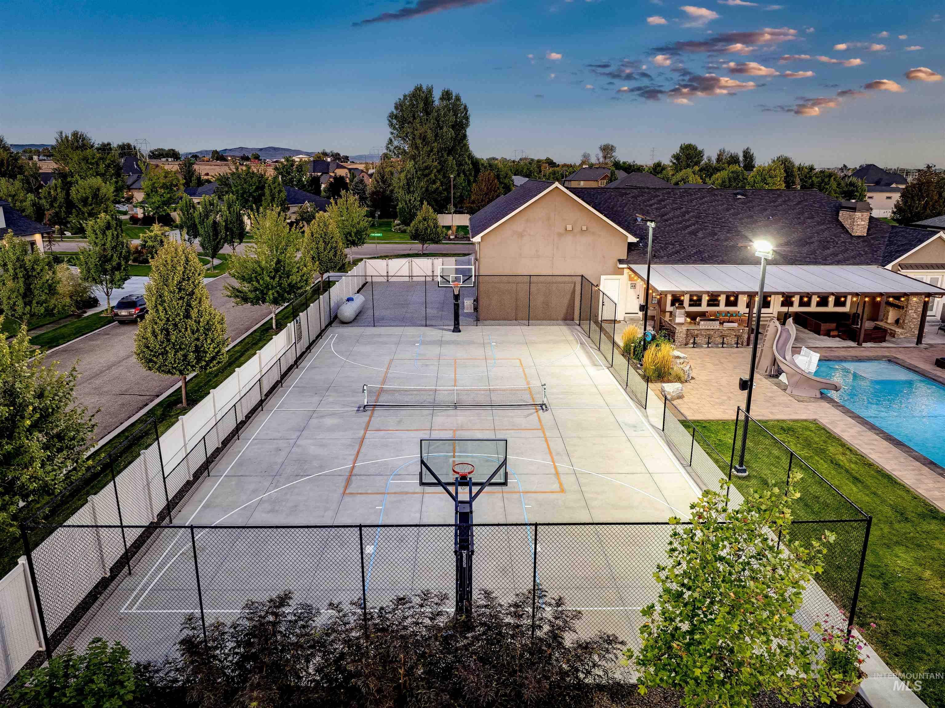 View of tennis court featuring basketball court and a patio area