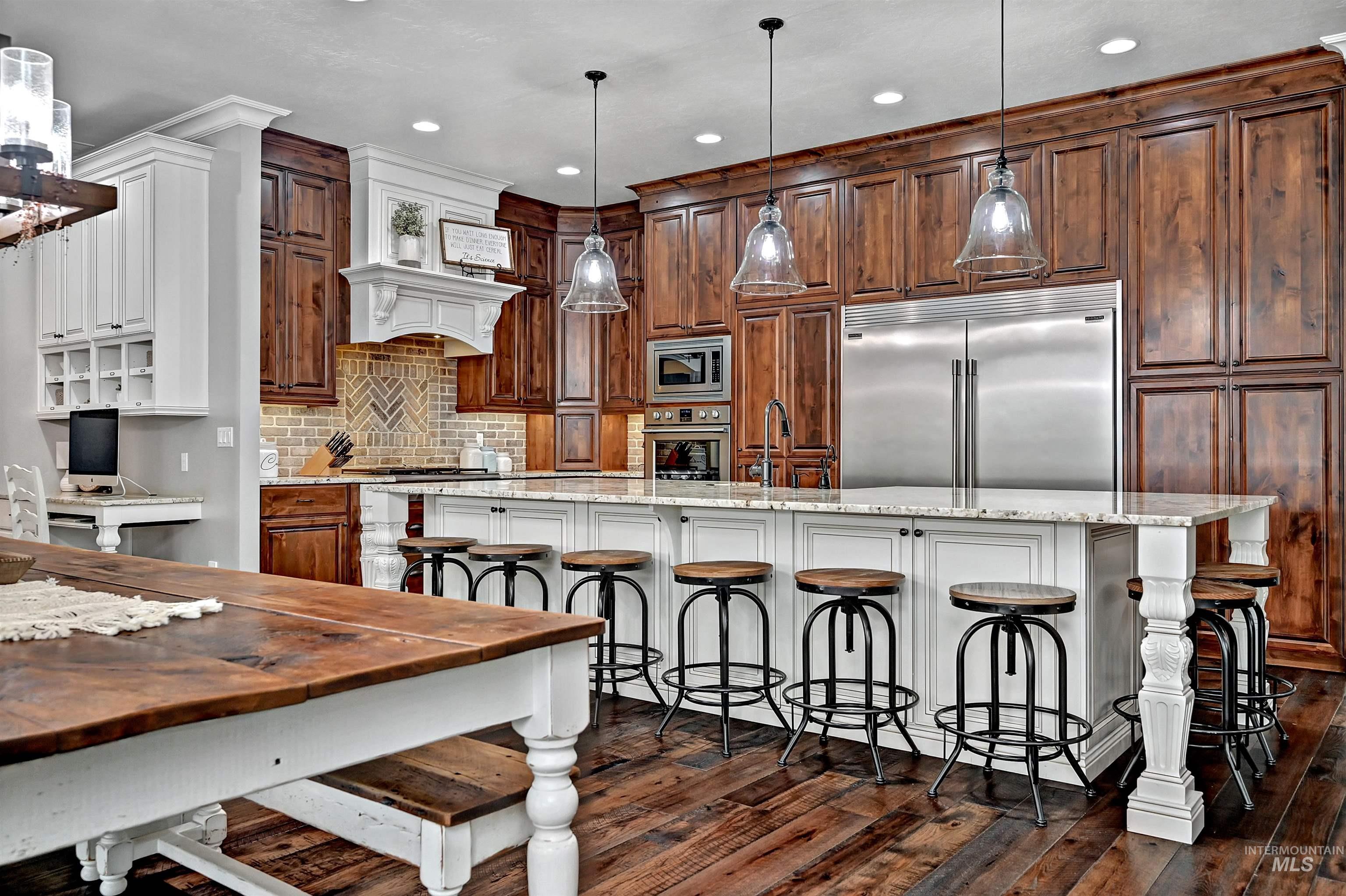 Kitchen with a kitchen bar, built in appliances, pendant lighting, a large island with sink, and recessed lighting