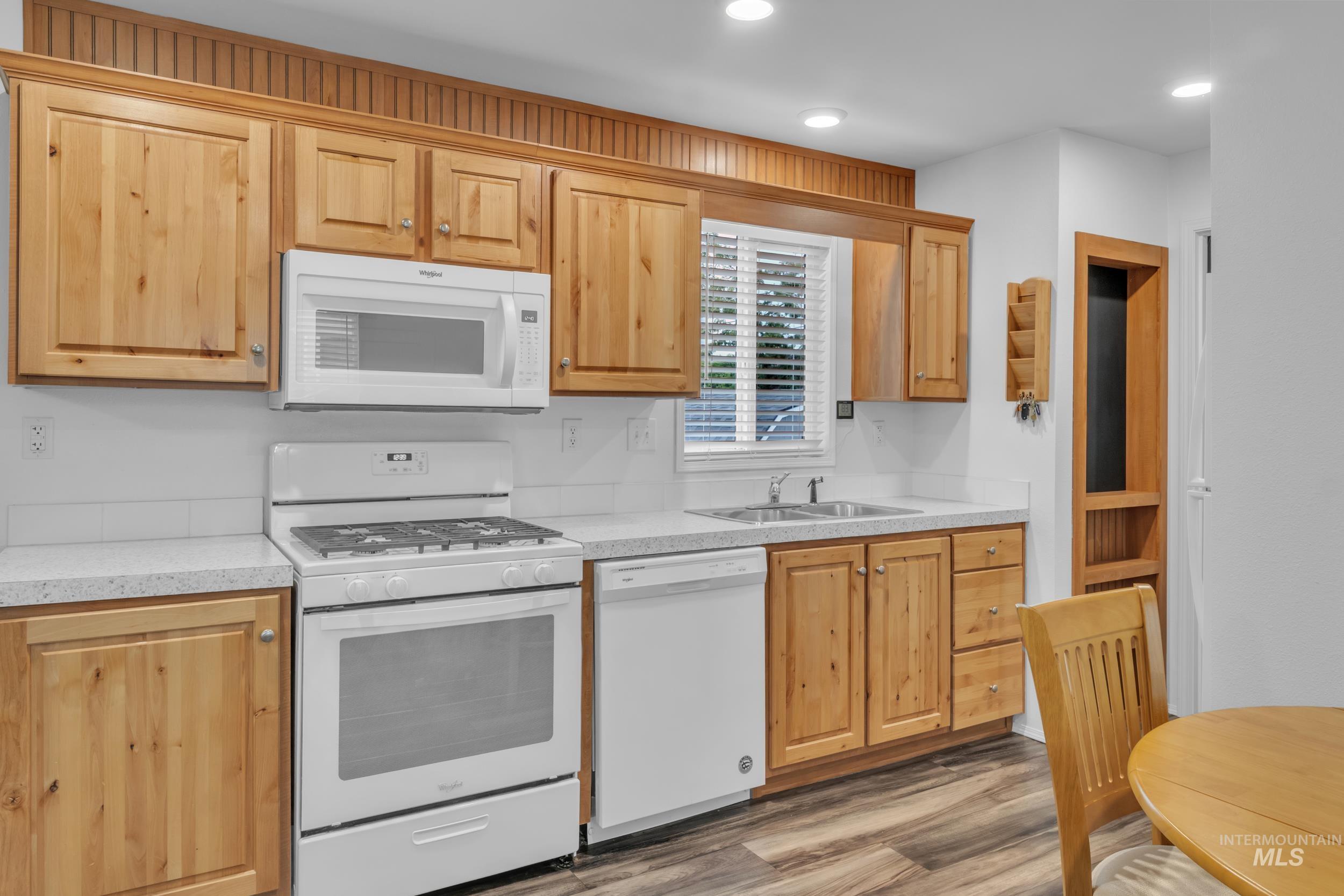 Kitchen featuring white appliances, light countertops, light wood-style flooring, recessed lighting, and light brown cabinets
