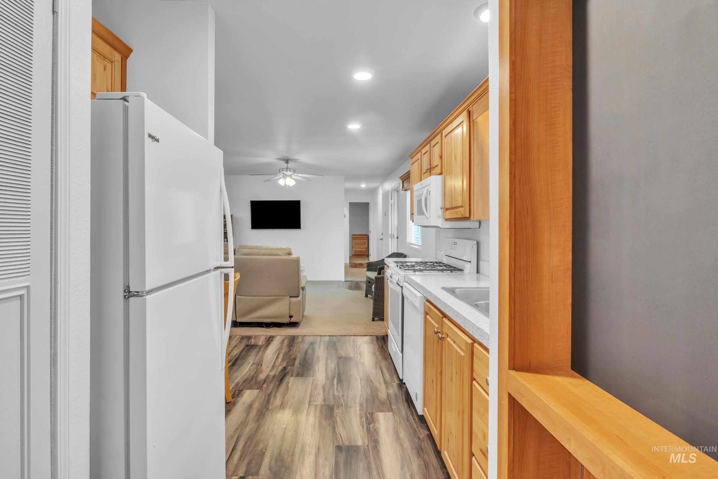 Kitchen with light countertops, white appliances, open floor plan, dark wood-style flooring, and recessed lighting