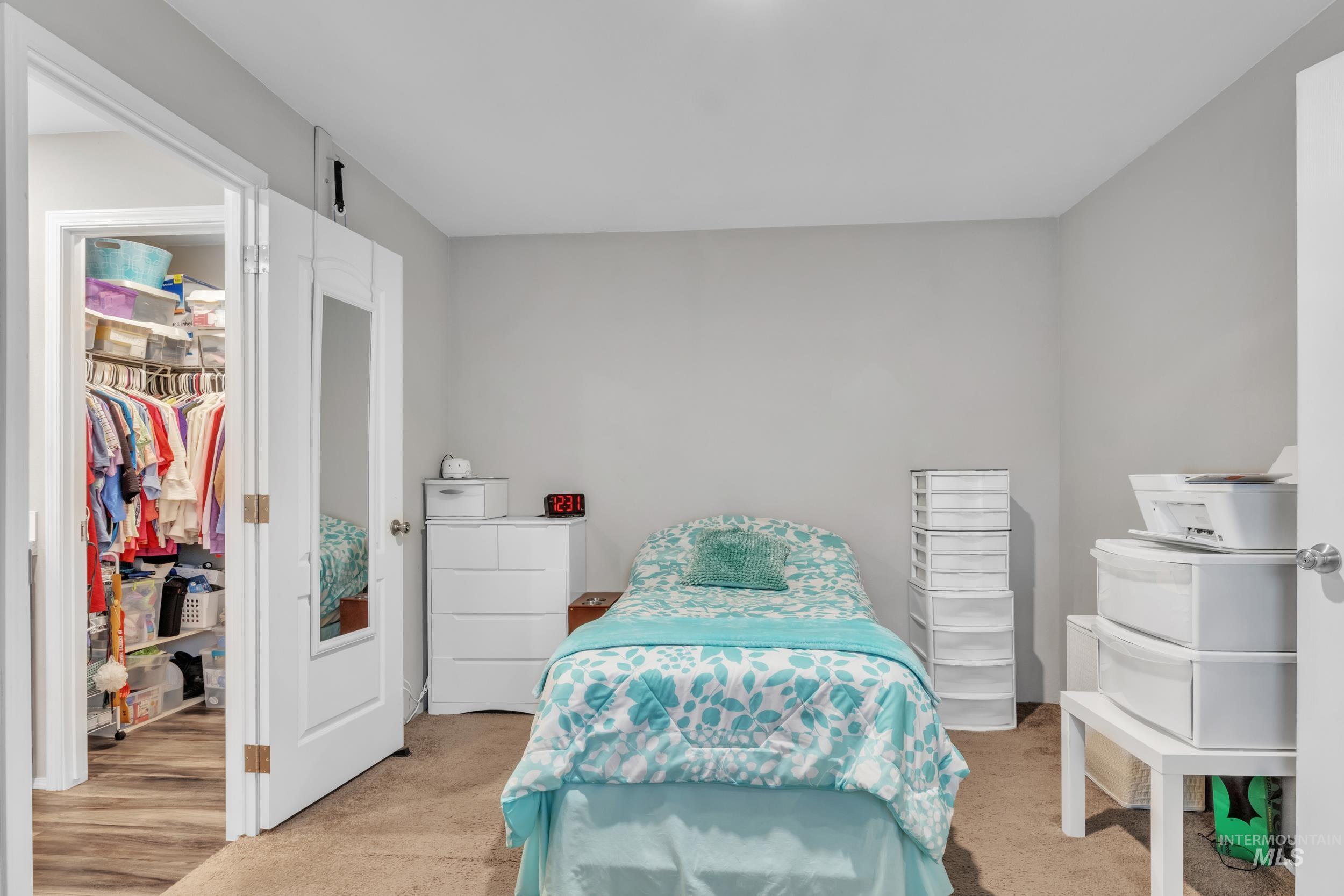 Bedroom featuring light colored carpet and a walk in closet