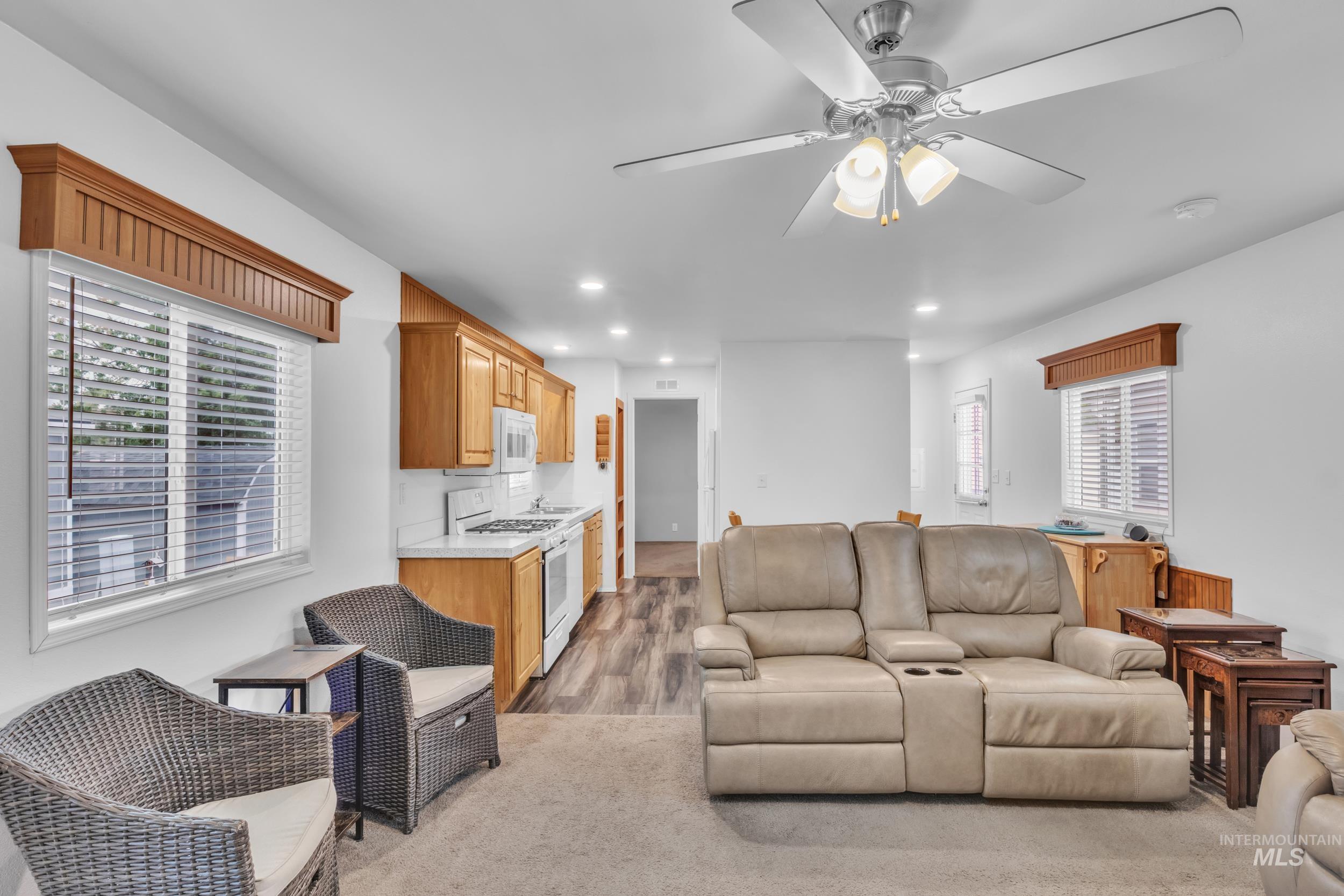 Living room featuring recessed lighting, ceiling fan, light colored carpet, and light wood-style flooring