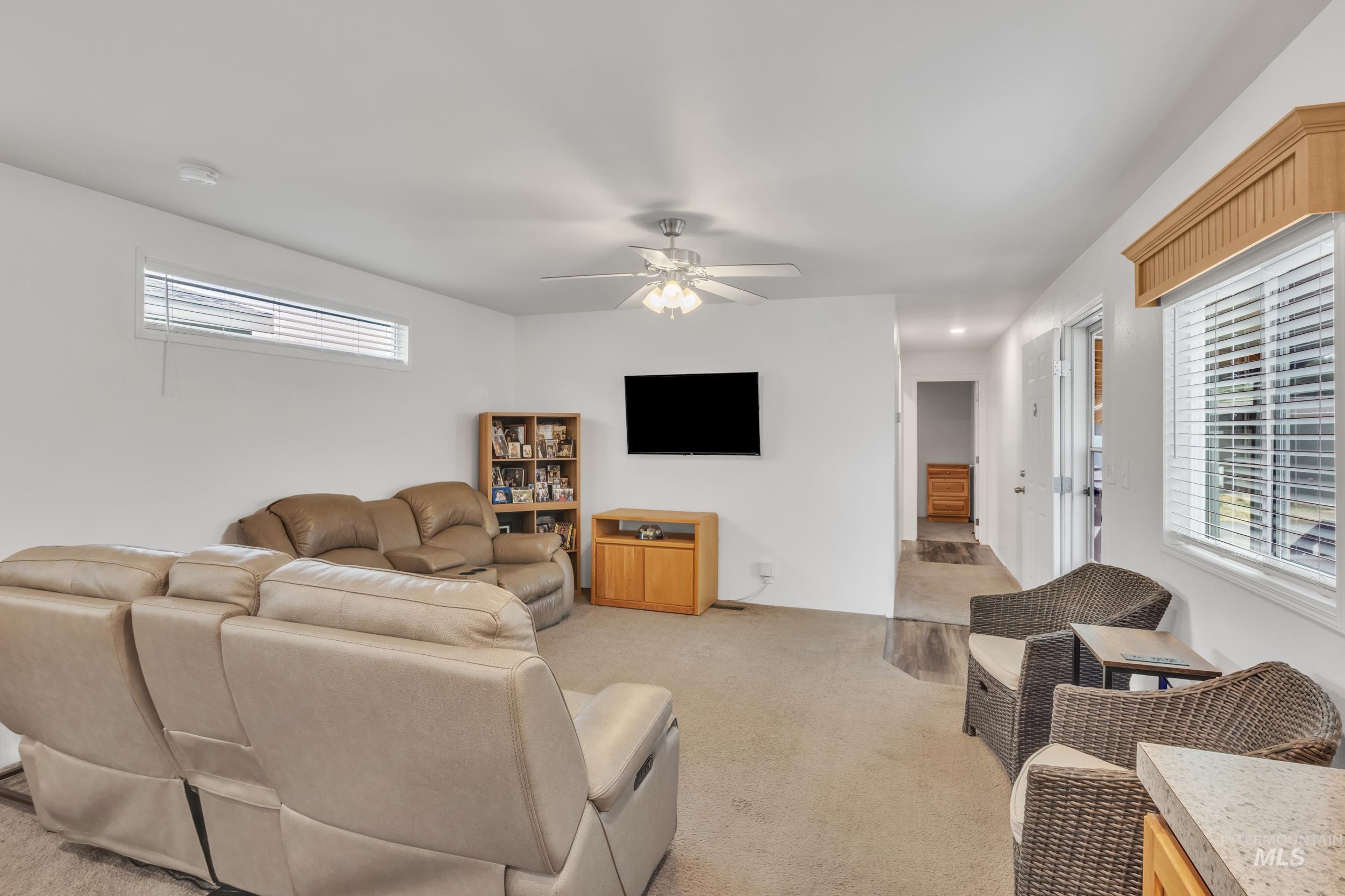 Living area with light carpet and ceiling fan