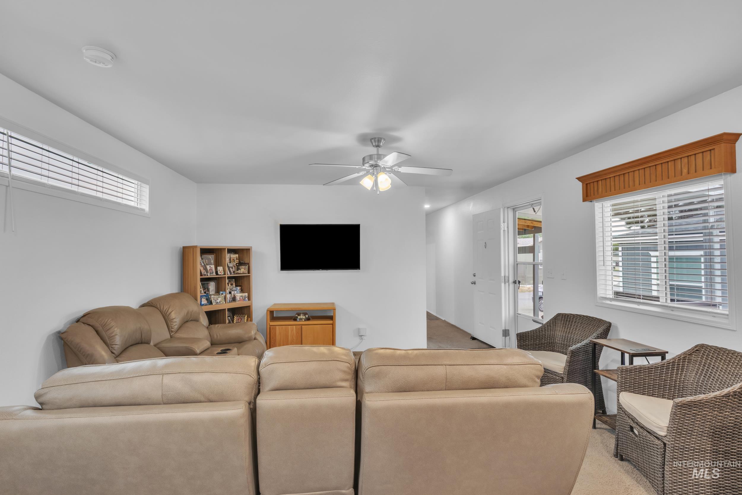 Carpeted living area featuring healthy amount of natural light and a ceiling fan